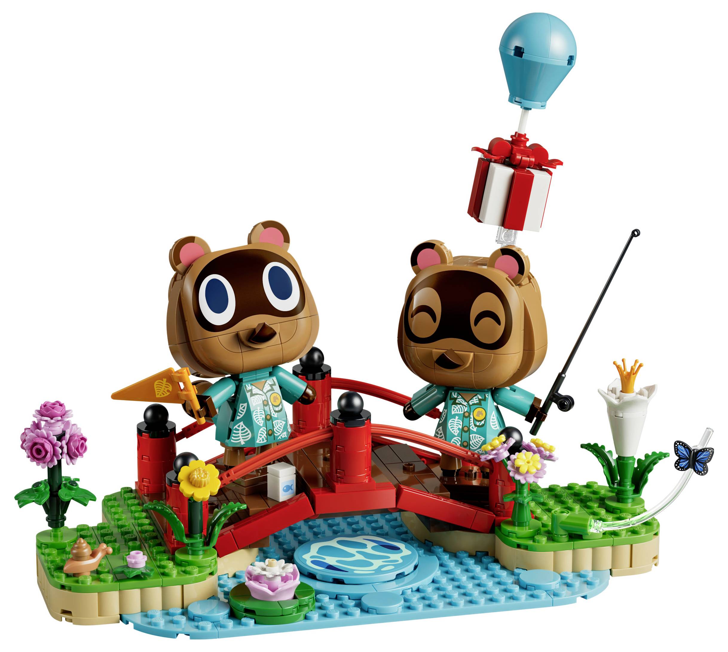 Zwei Bärenfiguren auf einer roten Brücke über einen blauen Bachlauf, eine angelt während ein Geschenk an einem Ballon hinabschwebt; LEGO-ähnliche Szene mit Blumen und Pflanzen.