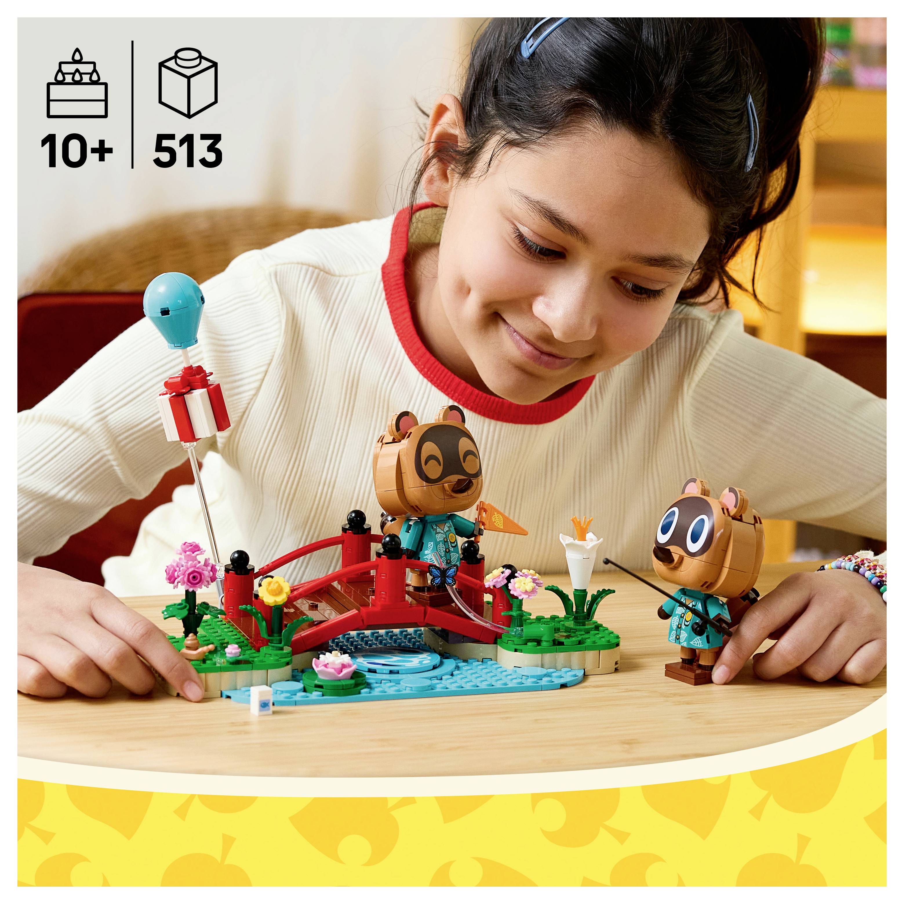 Mädchen spielt mit einem LEGO-ähnlichen Tierszenerie-Set auf einem Tisch, mit den Symbolen „10+