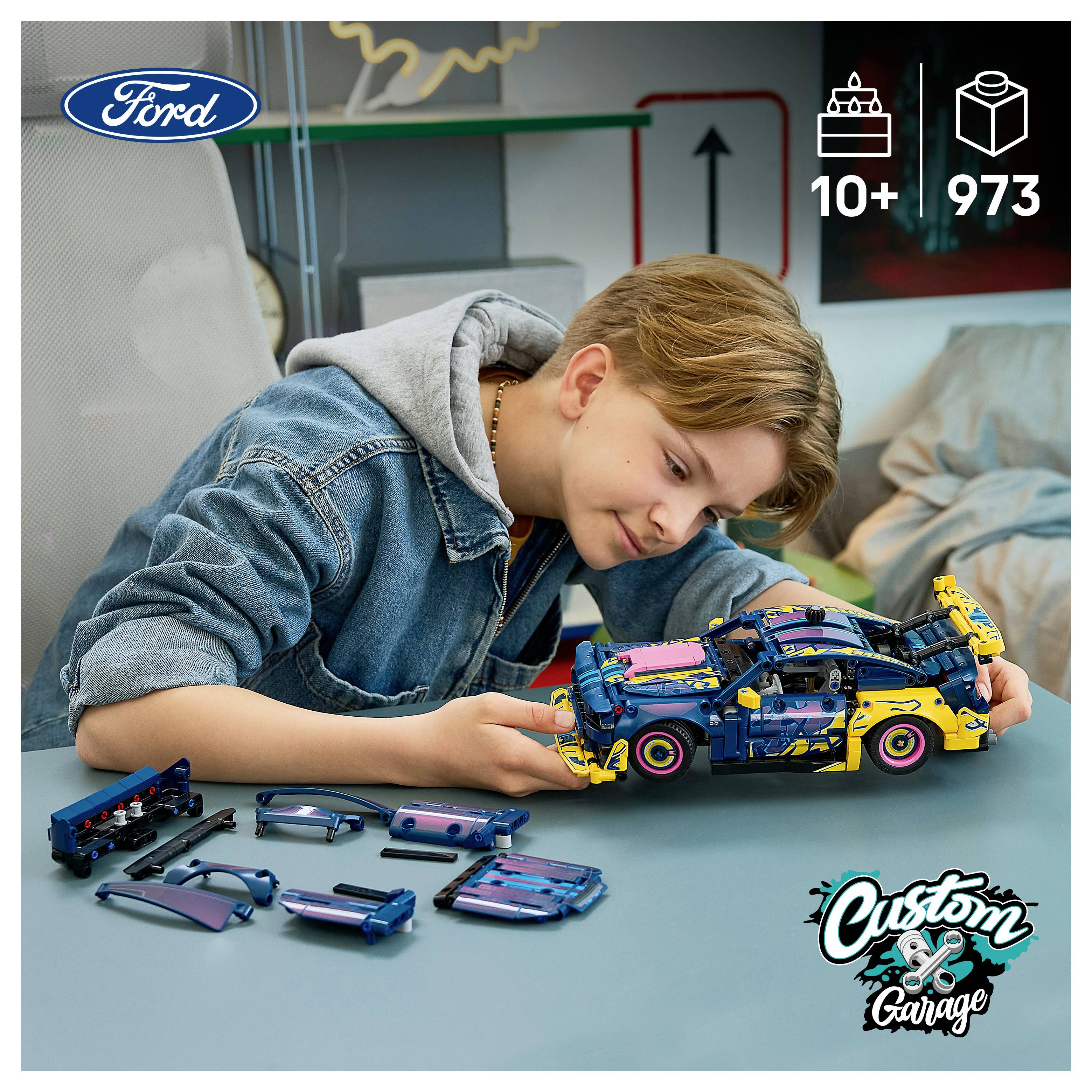 Junge, der ein LEGO-ähnliches Ford-Automodell an einem Tisch zusammenbaut, mit zerlegten Teilen neben ihm und „10+