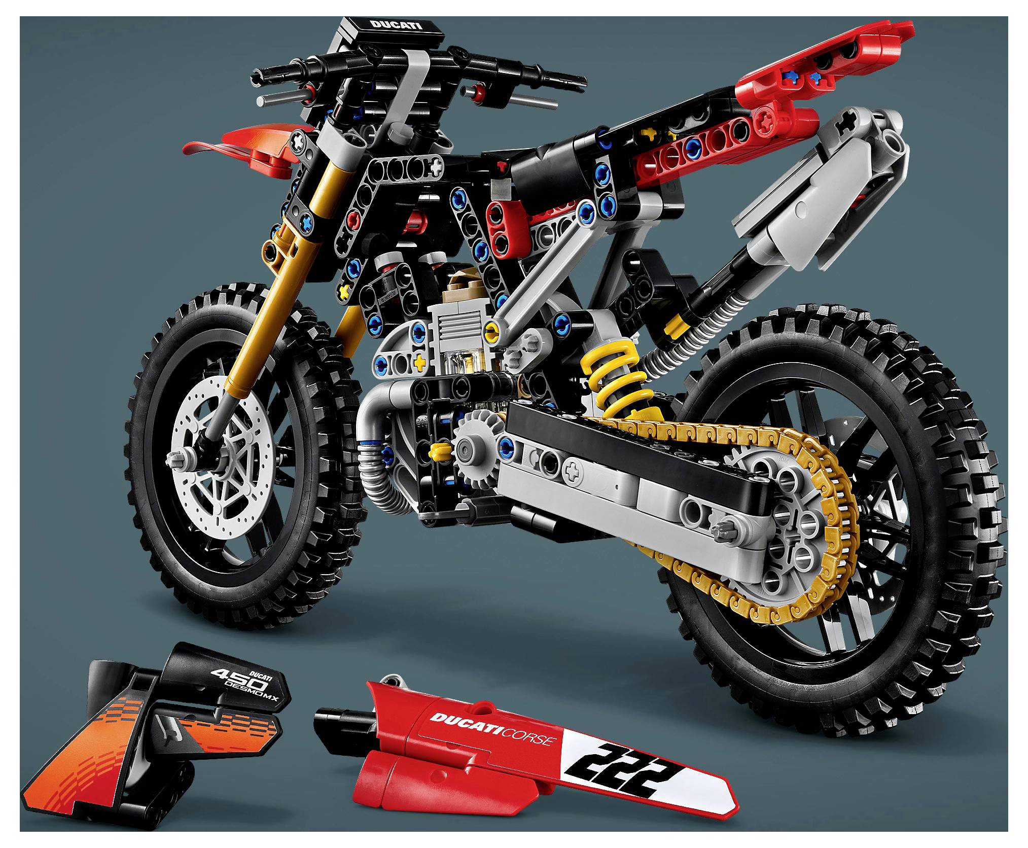 Explosionszeichnung eines LEGO Ducati Geländemotorrad-Modells mit unten gezeigten abgelösten Verkleidungsteilen, die seinen Rahmen, die Aufhängung, die Kette und die Räder hervorheben.