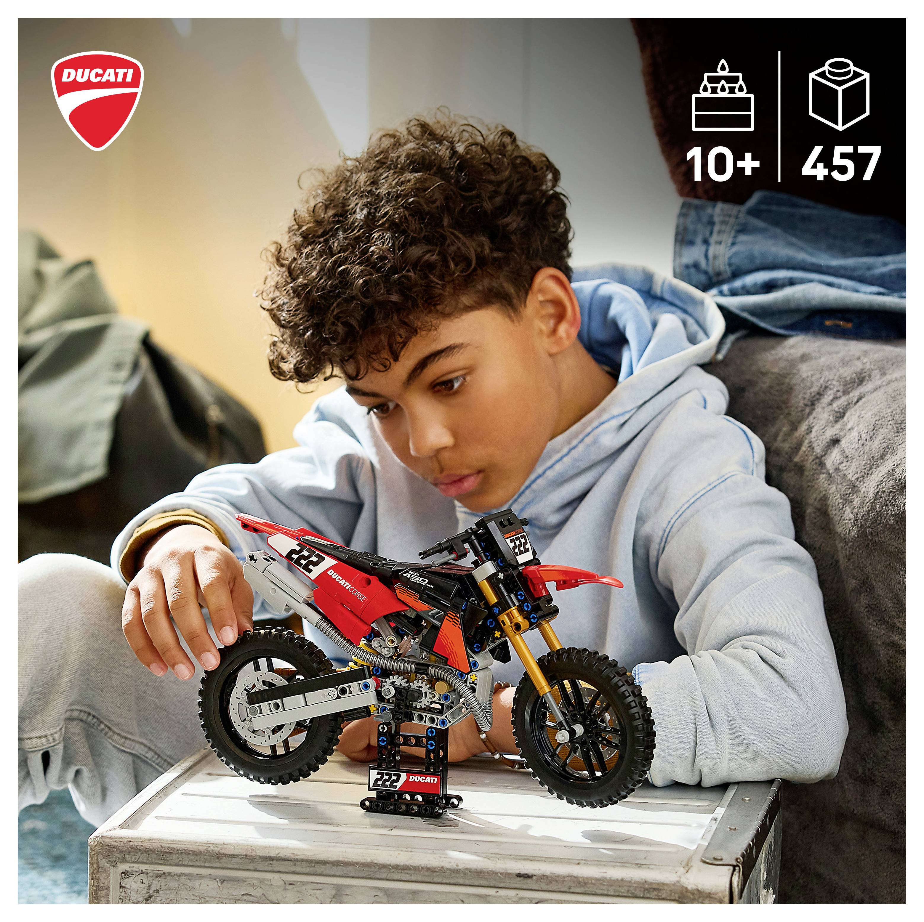 Junge, der ein Ducati-Motorradmodellbausatz auf einem Tisch zusammenbaut, mit angezeigten Altersangaben „10+