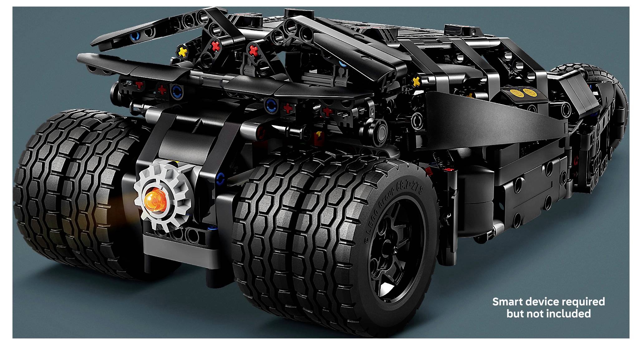 Rückansicht eines schwarzen LEGO-ähnlichen Fahrzeugchassis mit großen Doppelhinterreifen und sichtbarem Fahrwerk; Text besagt 