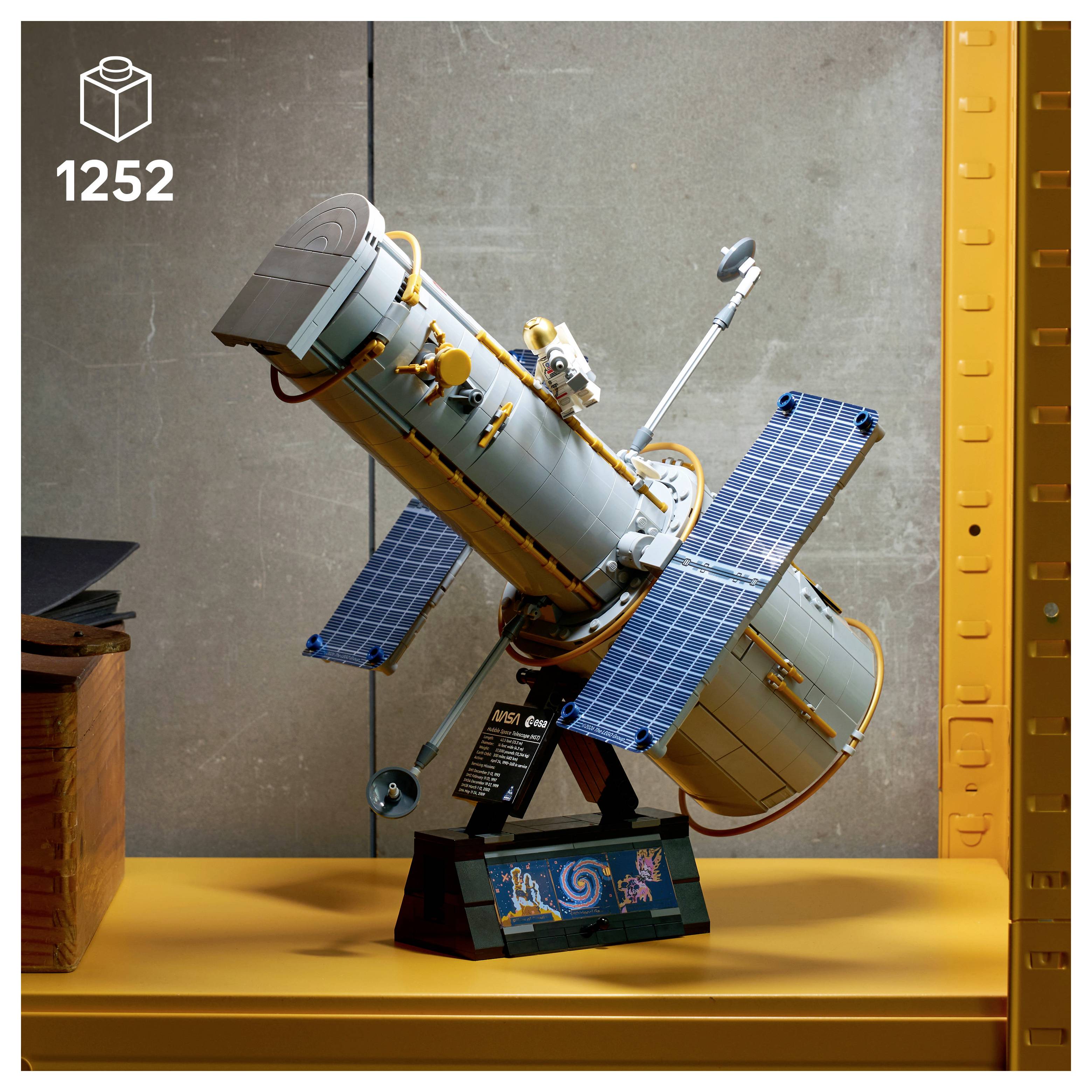 Ein Modell eines Weltraumteleskops mit blauen Solarpanelen auf einem Ausstellungsregal, beschriftet mit „1252