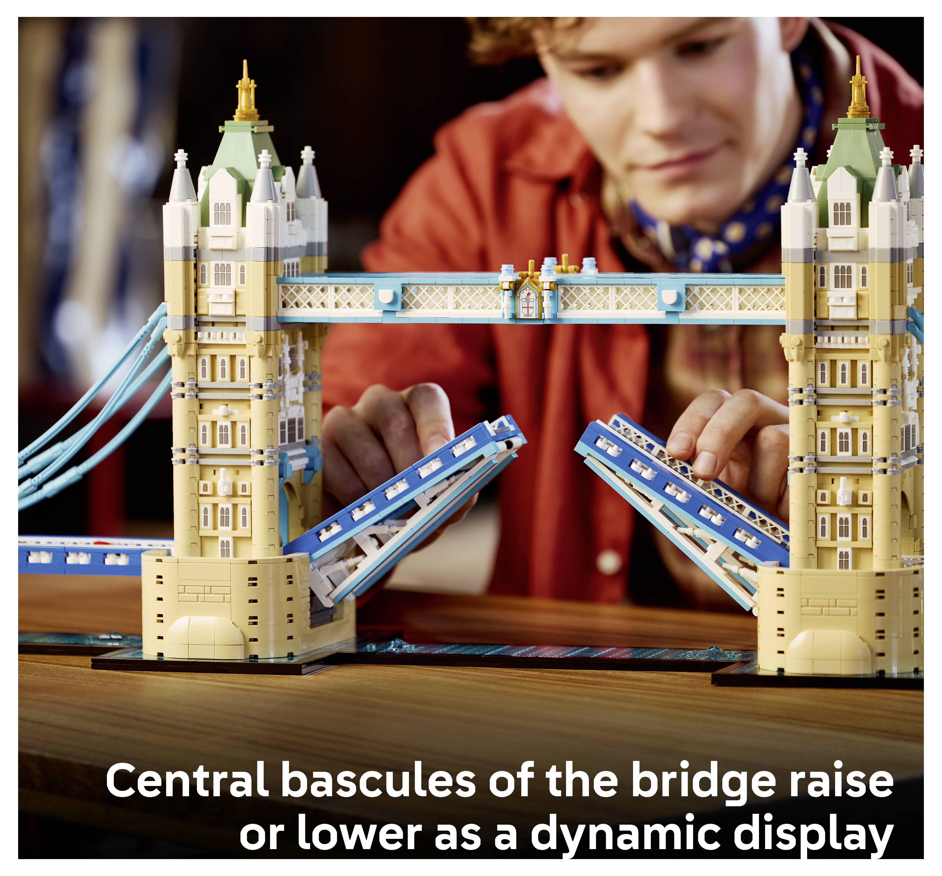 Eine Person, die ein LEGO-Modell der Tower Bridge baut, wobei die mittleren Hubbrücken hochgefahren sind; die Bildunterschrift lautet „Die zentralen Hubbrücken der Brücke fahren auf oder ab als dynamische Anzeige