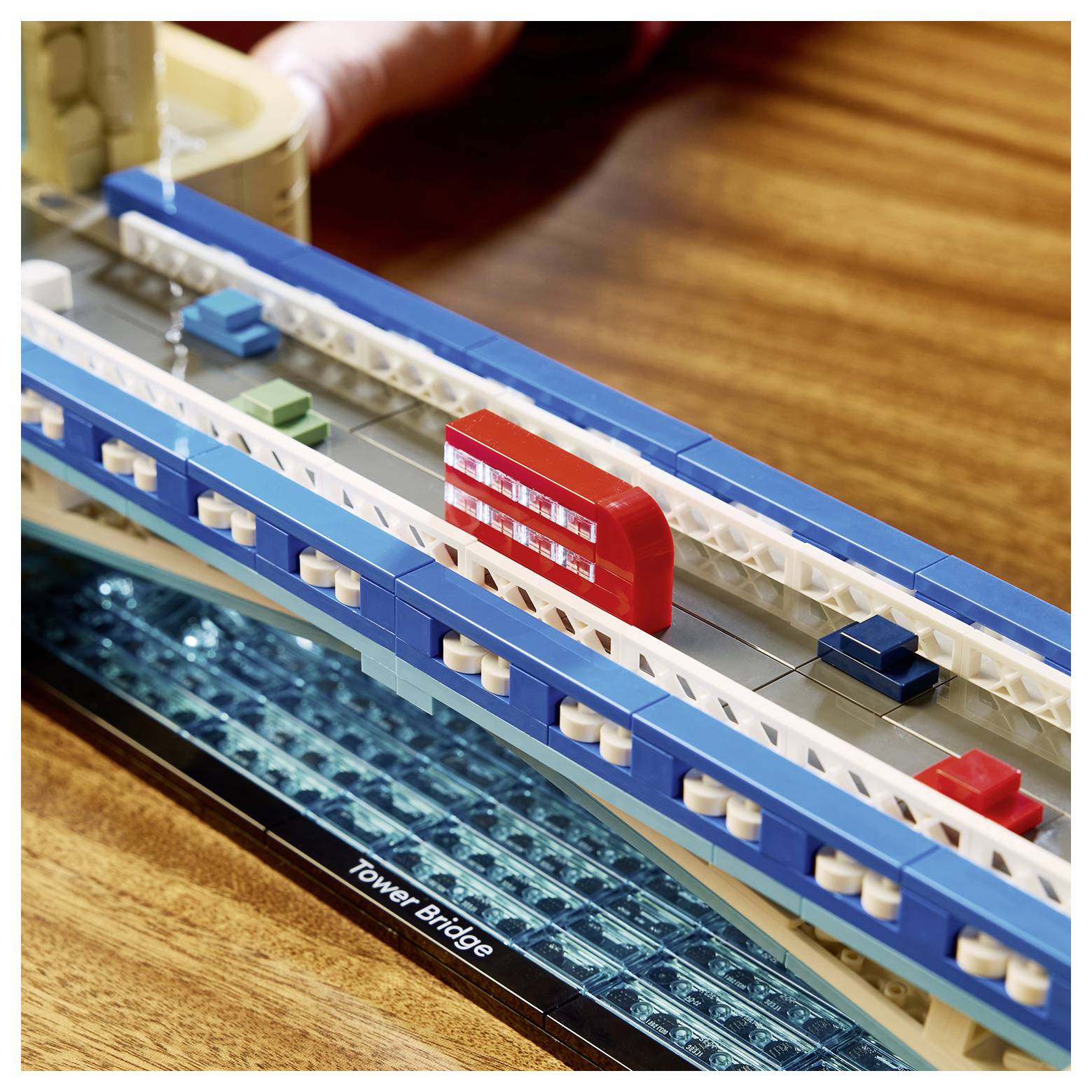 LEGO-Modell der Tower Bridge auf einem Holztisch, mit einem roten Doppeldeckerbus, der über die Brückenspanne fährt.