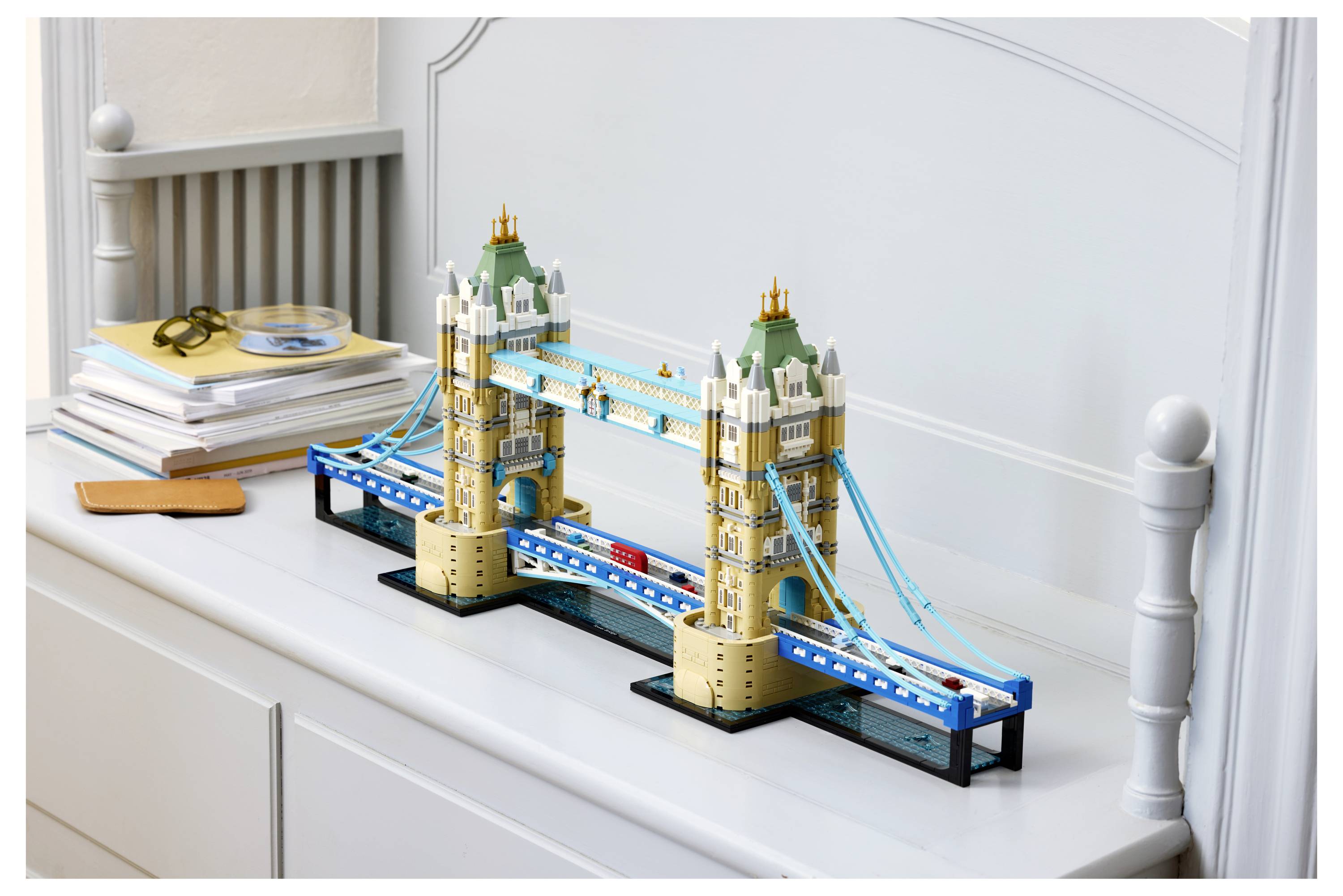 LEGO-Modell der Tower Bridge in London, das auf einem weißen Sideboard neben Büchern und Brillen ausgestellt ist.