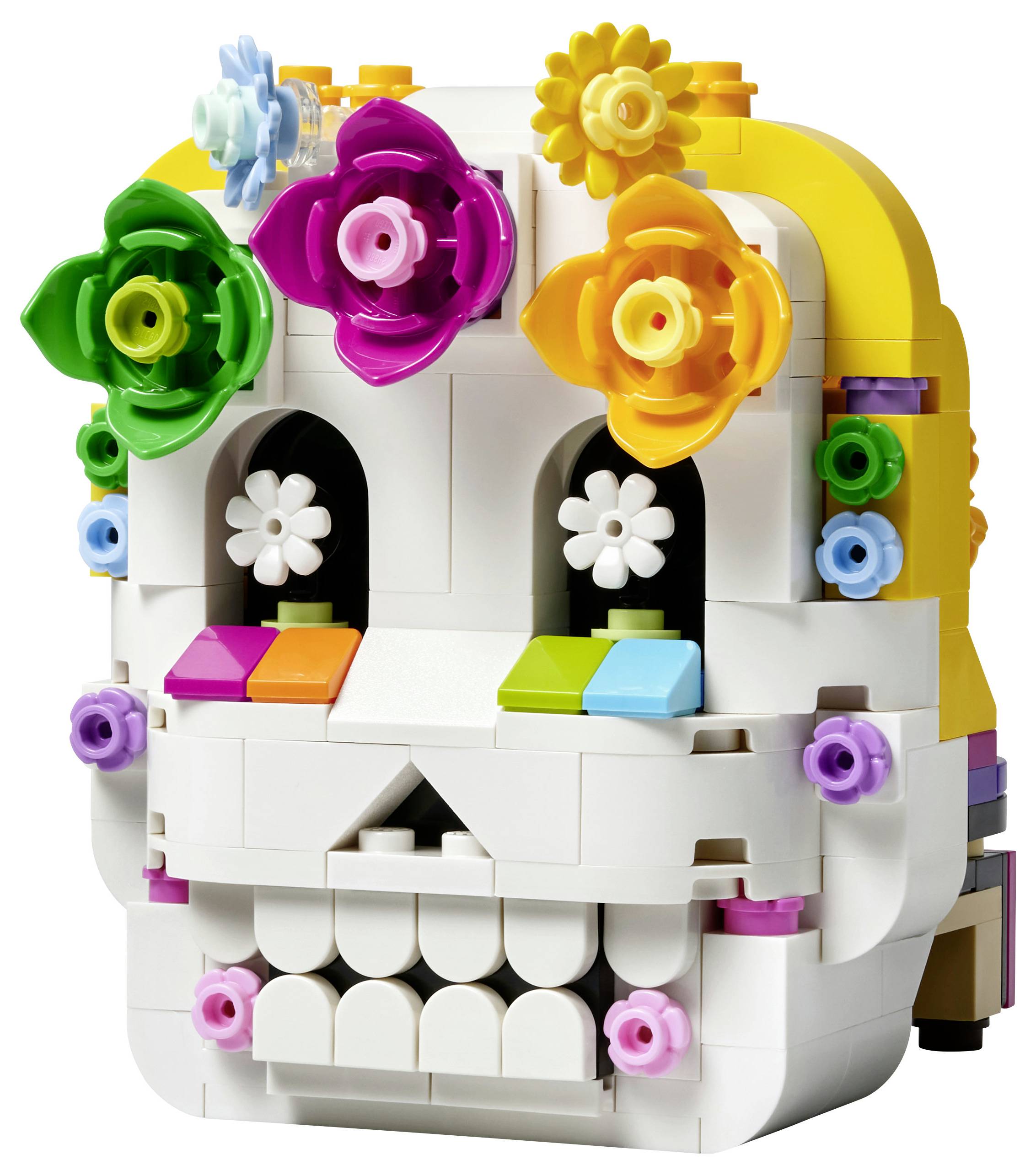 Bunte LEGO-ähnliche Schädelskulptur mit Blumenverzierungen, Vorderansicht auf weißem Hintergrund.