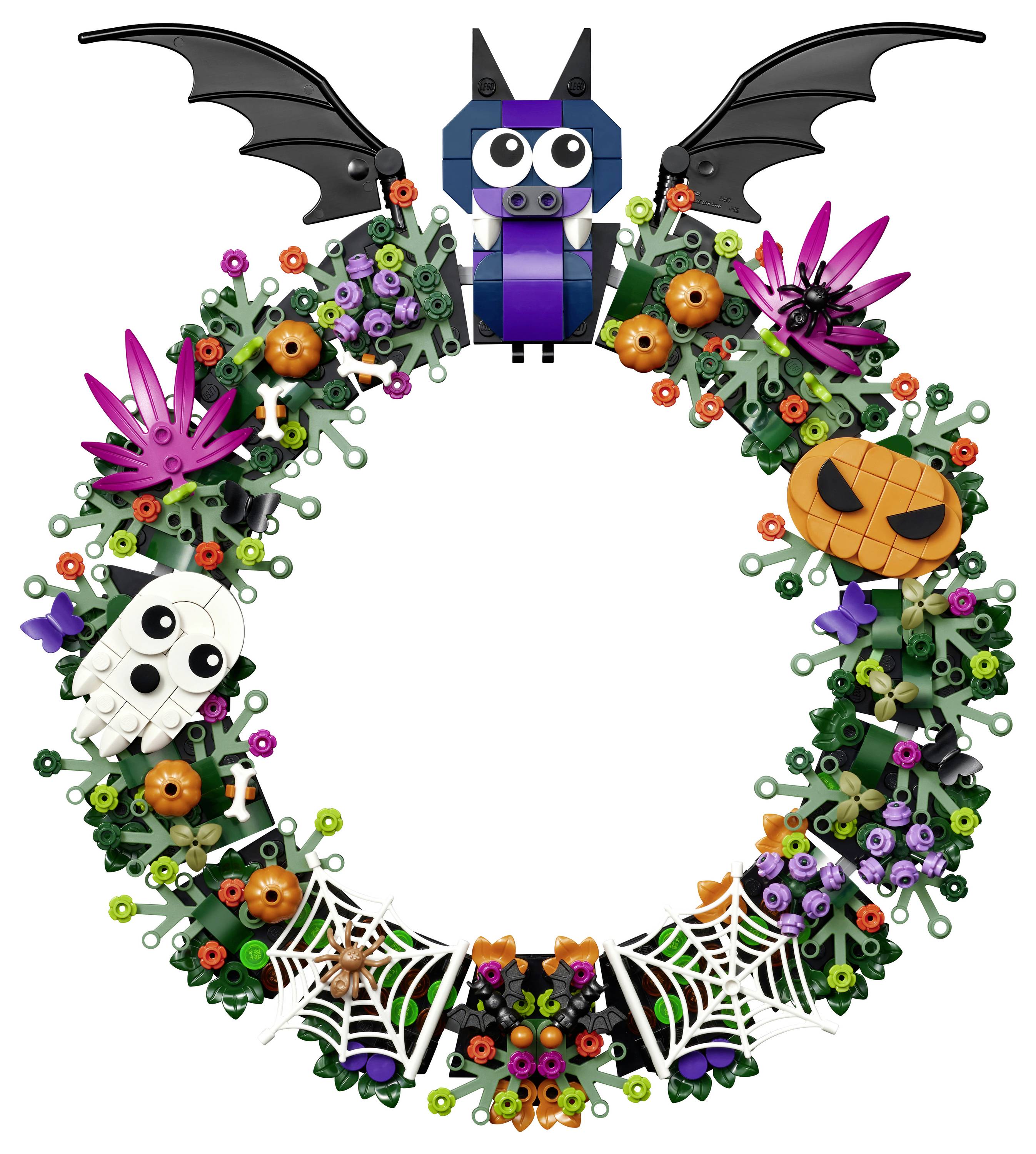 Herbstkranz mit einer Fledermaus oben, lila Blumen, orangenem Kürbis, Schädel, Spinnweben und einer Spinne auf einem kreisförmigen grünen Rankenrahmen.