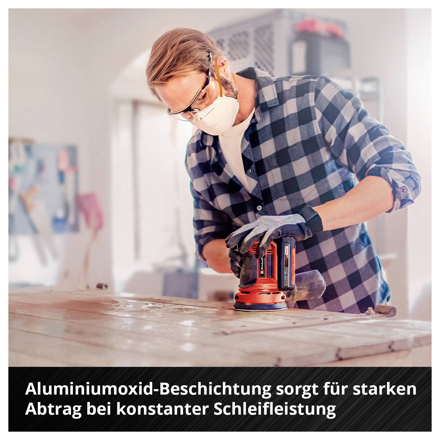Mann mit Schutzbrille und Maske schleift eine Holzplatte mit einem Exzenterschleifer; unten steht: 'Aluminiumoxid-Beschichtung sorgt für starken Abtrag bei konstanter Schleifleistung'.