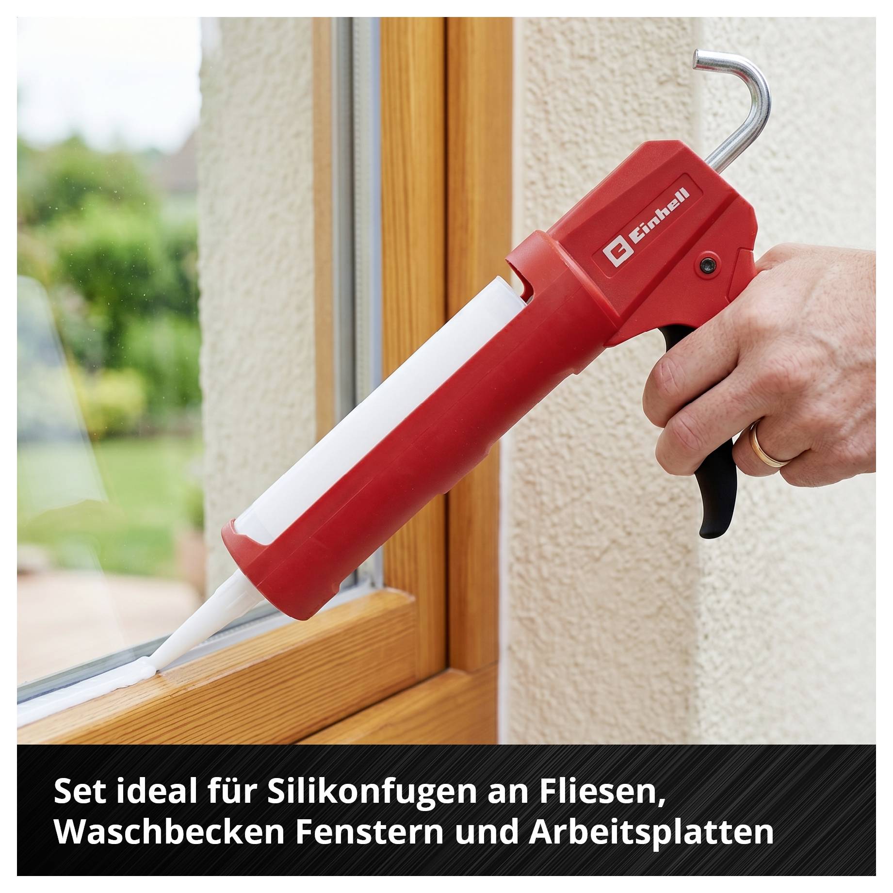 Hand hält rote Auspresspistole für Silikon an einem Fensterrahmen; Hinweistext: 'Set ideal für Silikonfugen an Fliesen, Waschbecken, Fenstern und Arbeitsplatten'