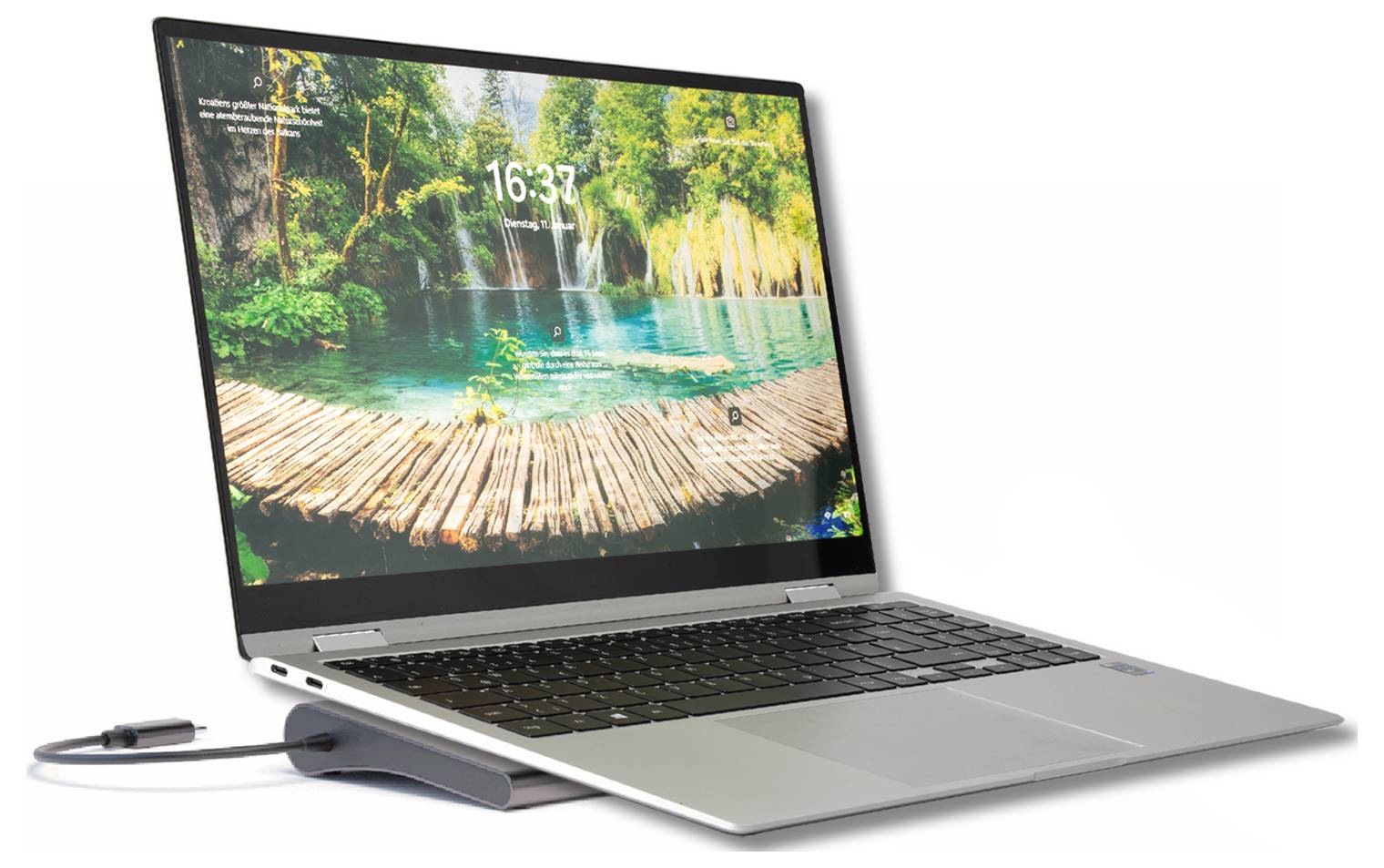 Laptop mit einem landschaftlichen Wasserfall-Sperrbildschirm und einem angeschlossenen Kabel/Dongle auf der linken Seite offen.