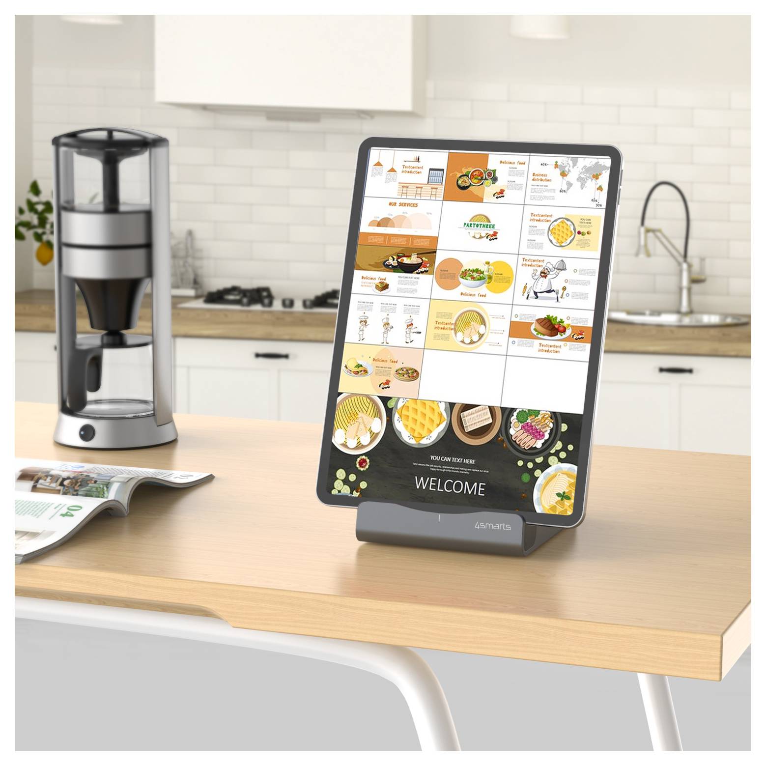 Ein Tablet auf einem Küchentisch zeigt ein farbenfrohes Essen- und Rezeptmenü an, mit einer Kaffeemaschine, einer offenen Zeitschrift und einem Spülbecken im Hintergrund.