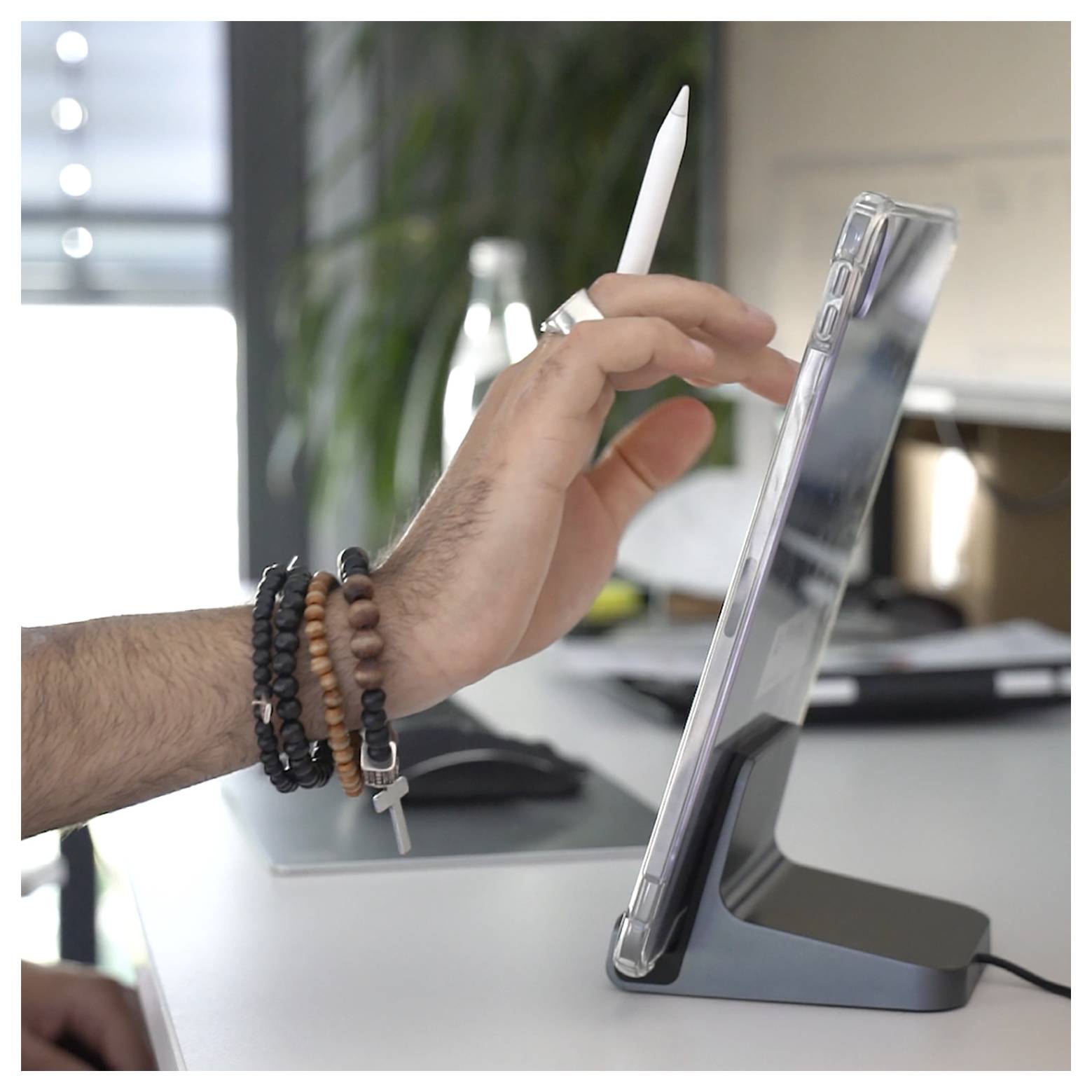 Hand benutzt einen Stylus auf einem Tablet in einem Desktop-Ständer auf einem Schreibtisch.