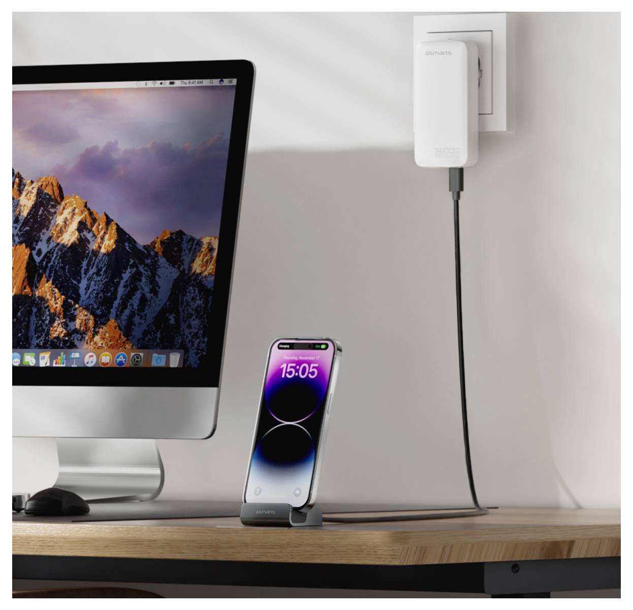 Desktop-Setup mit einem iMac und einem iPhone auf einem Ständer, das von einem Netzteil aufgeladen wird, mit einem Kabel, das zum Schreibtisch führt.