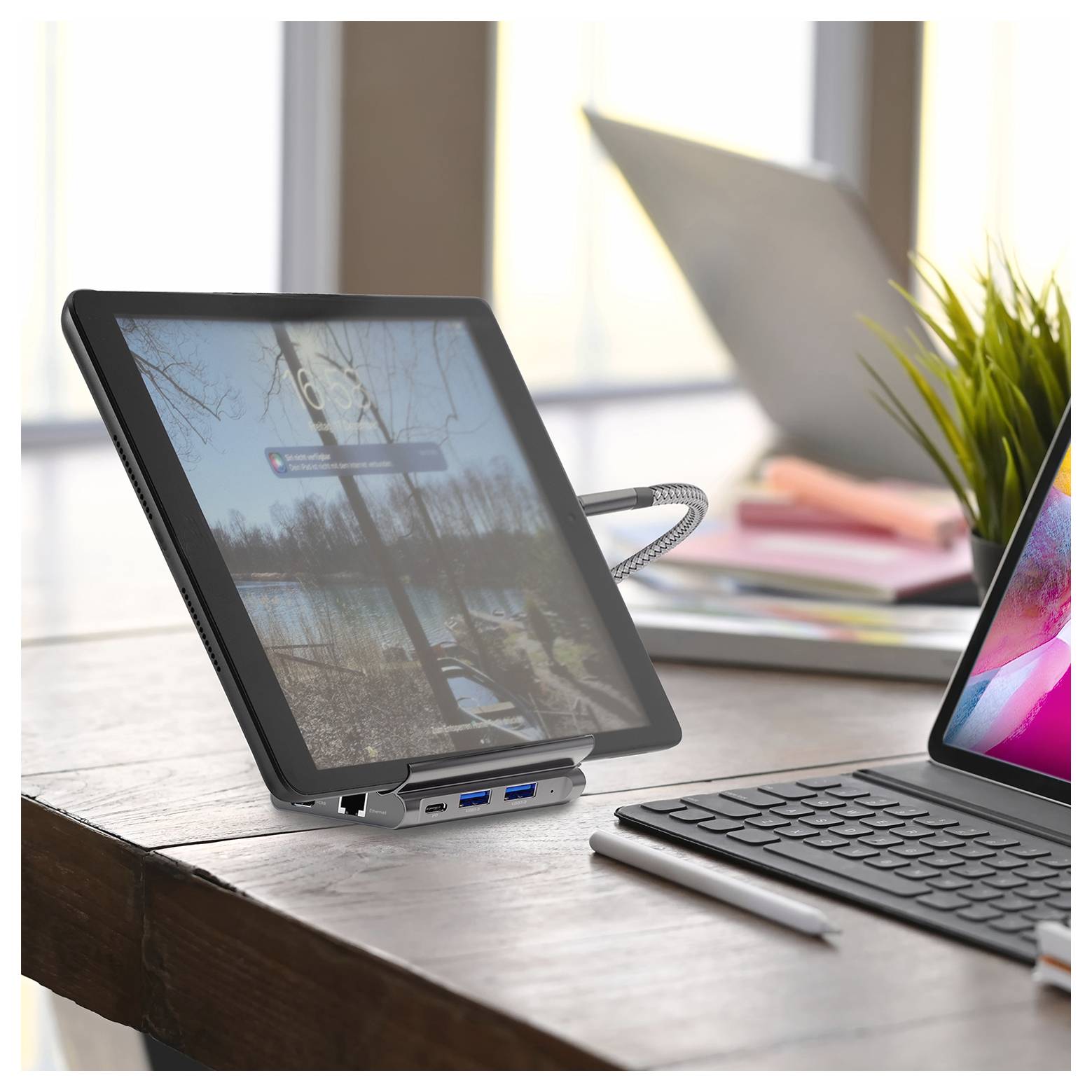 Tablet auf einem Schreibtisch über eine Dockingstation mit einem Laptop verbunden, mit gespiegeltem Bildschirm in einem hellen Homeoffice-Setup.