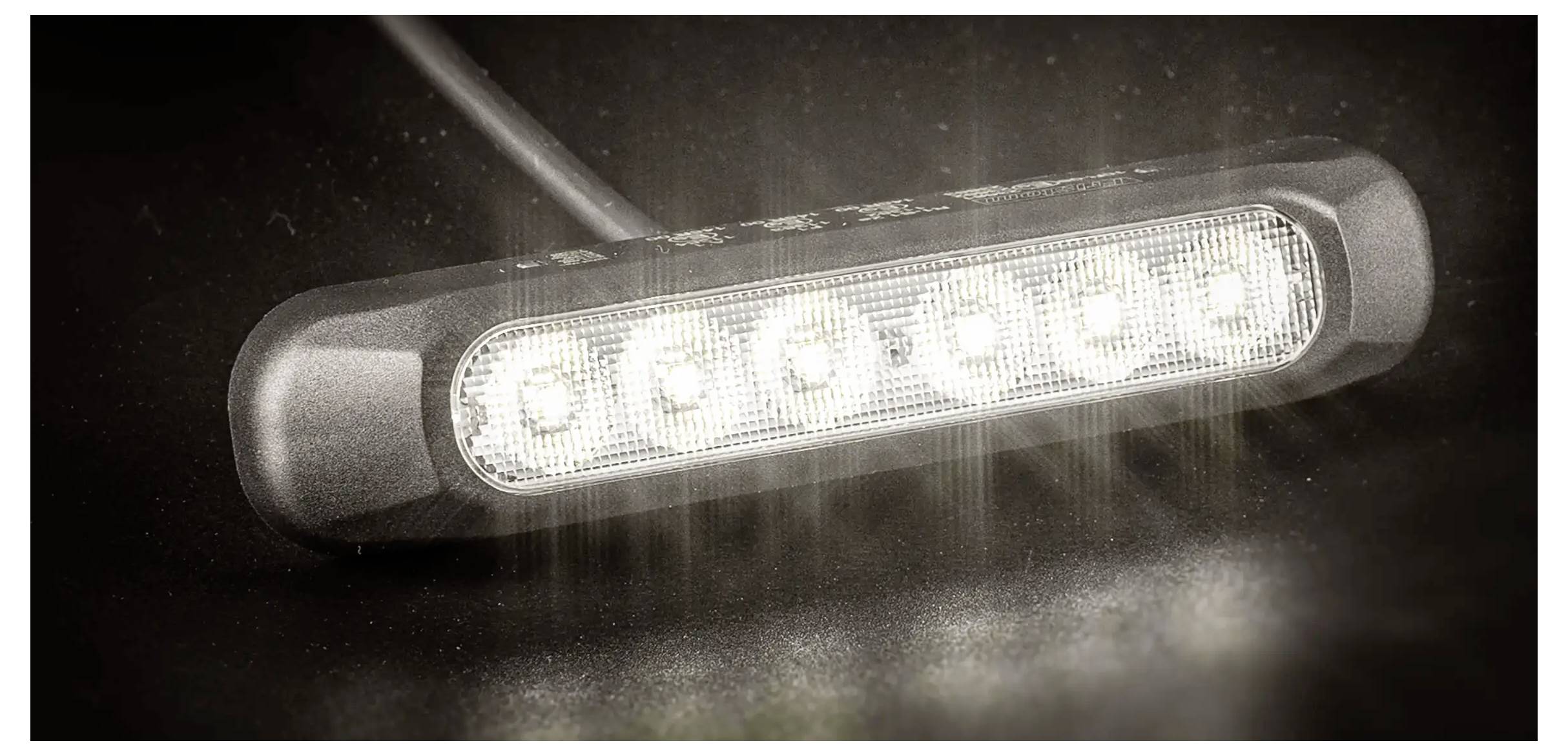 Schwarze LED-Lichtleiste, die in einer Nahaufnahme-Produktaufnahme hell leuchtet, mit dunklem Hintergrund und sichtbarem Linsenfla­re.