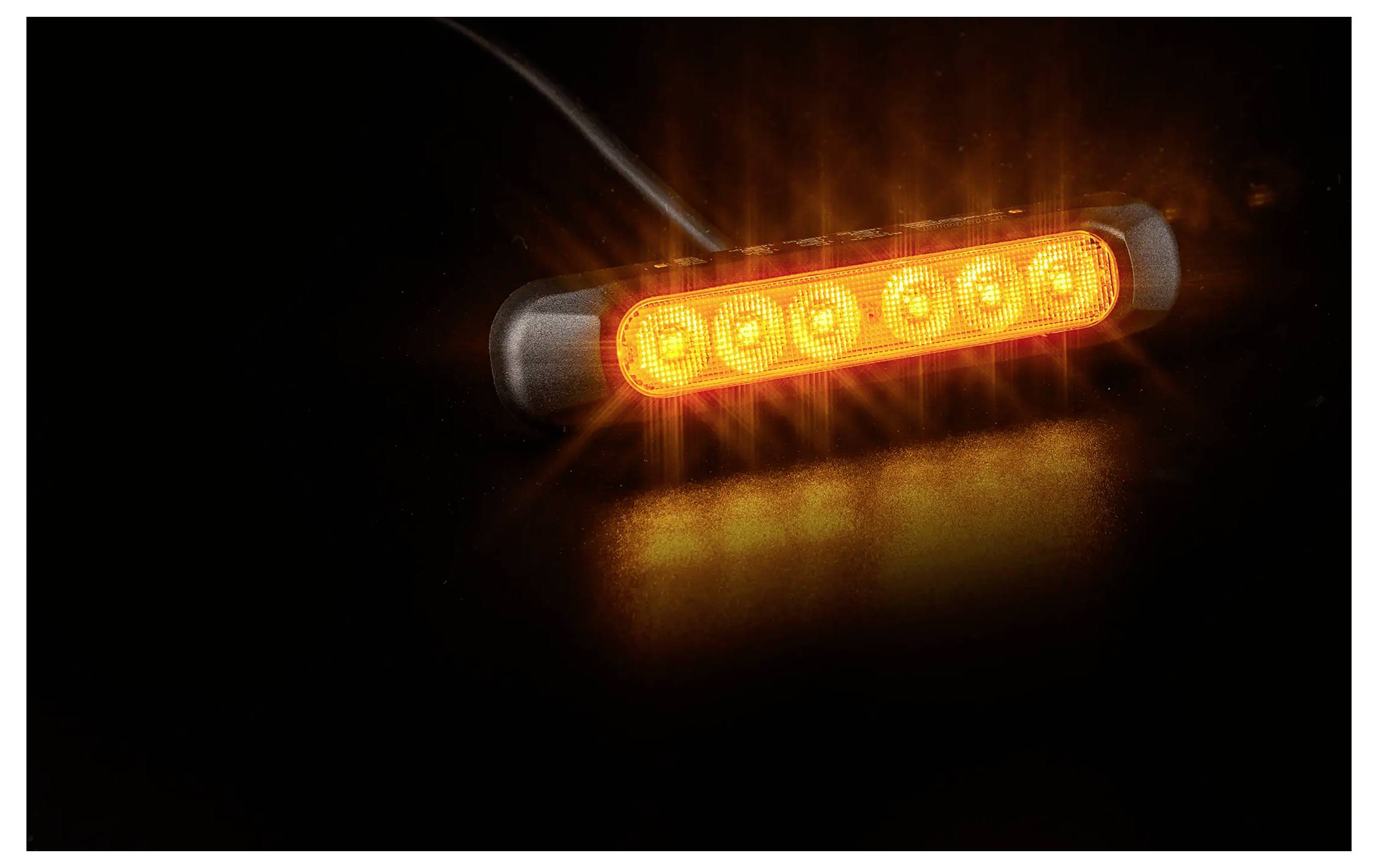 Oranges LED-Warnlicht, das im Dunkeln auf schwarzem Hintergrund leuchtet, in Nahaufnahme gezeigt.