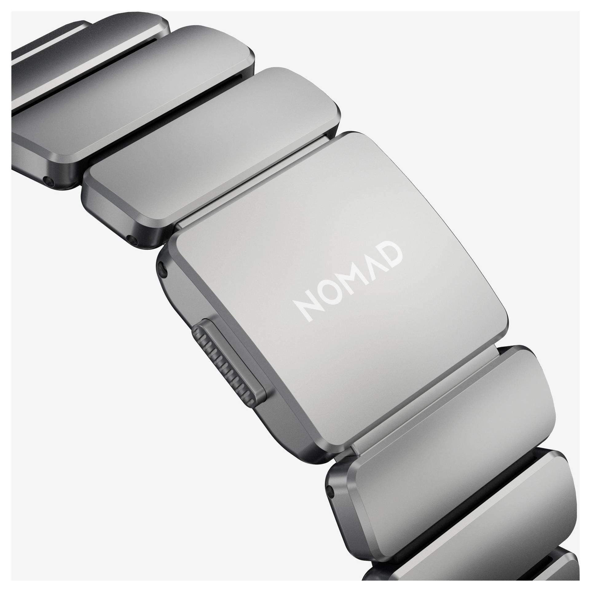 Silbernes Metall-Armband für Armbanduhr mit rechteckiger Schließe mit der Aufschrift "NOMAD" auf weißem Hintergrund.