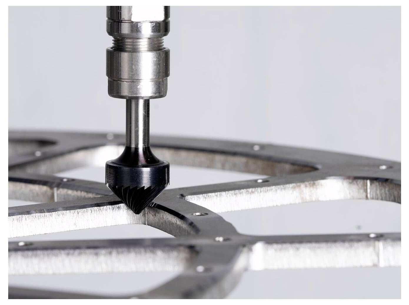 Nahaufnahme eines CNC-Fräswerkzeugs, das ein Metallteil bearbeitet und einen gekrümmten Schlitz in ein bearbeitetes Werkstück formt.