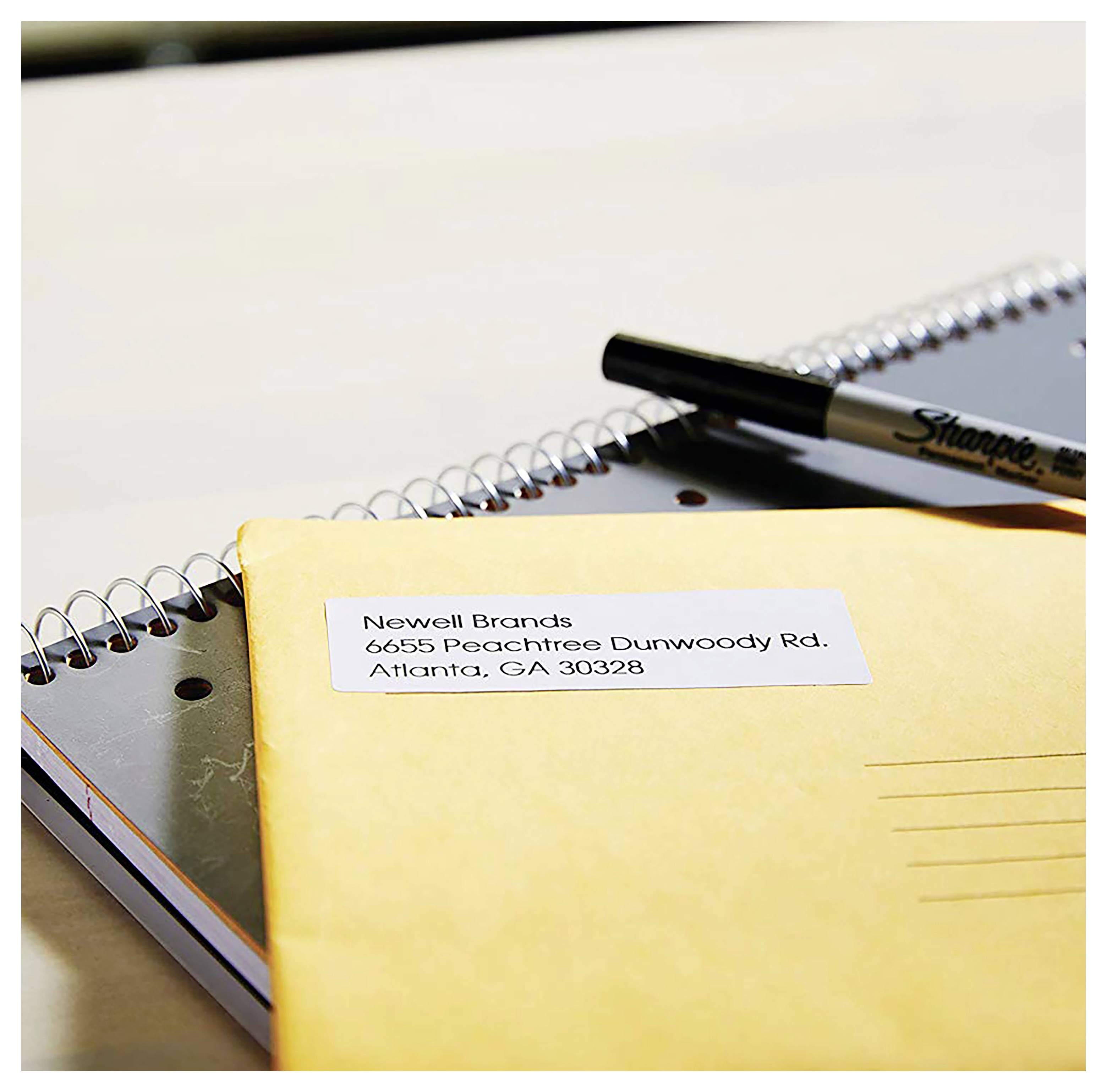 Gelber Umschlag auf einem Notizbuch mit einem Versandetikett mit der Aufschrift „Newell Brands, 6655 Peachtree Dunwoody Rd., Atlanta, GA 30328