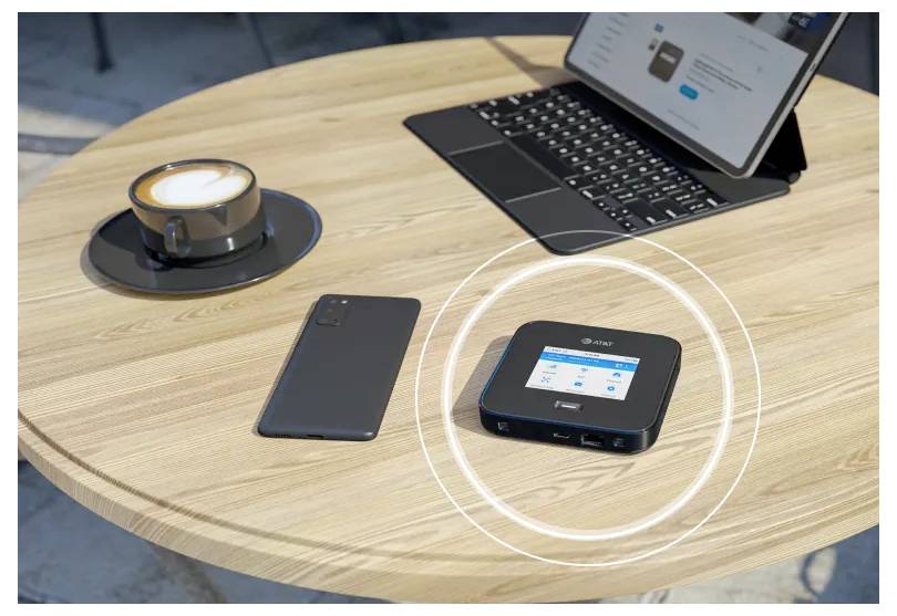 Tabletop-Arbeitsplatz mit einem Laptop, Smartphone, Kaffee und einem kleinen Hub/Gerät, die durch leuchtende Kreise hervorgehoben werden, was auf Konnektivität oder kabelloses Laden hindeutet.