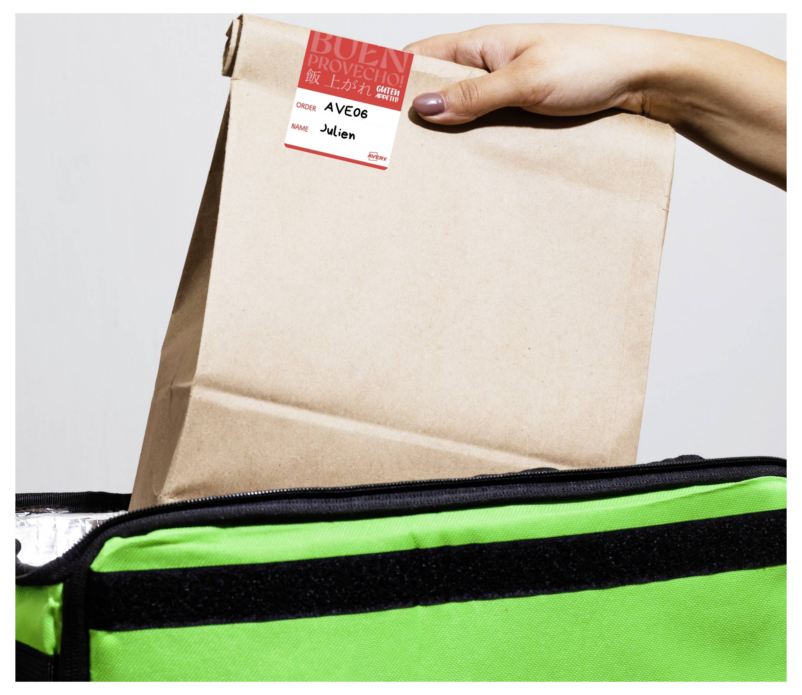 Eine Hand legt eine braune Papiertüte mit einem Bestelletikett in eine grüne isolierte Liefertasche.