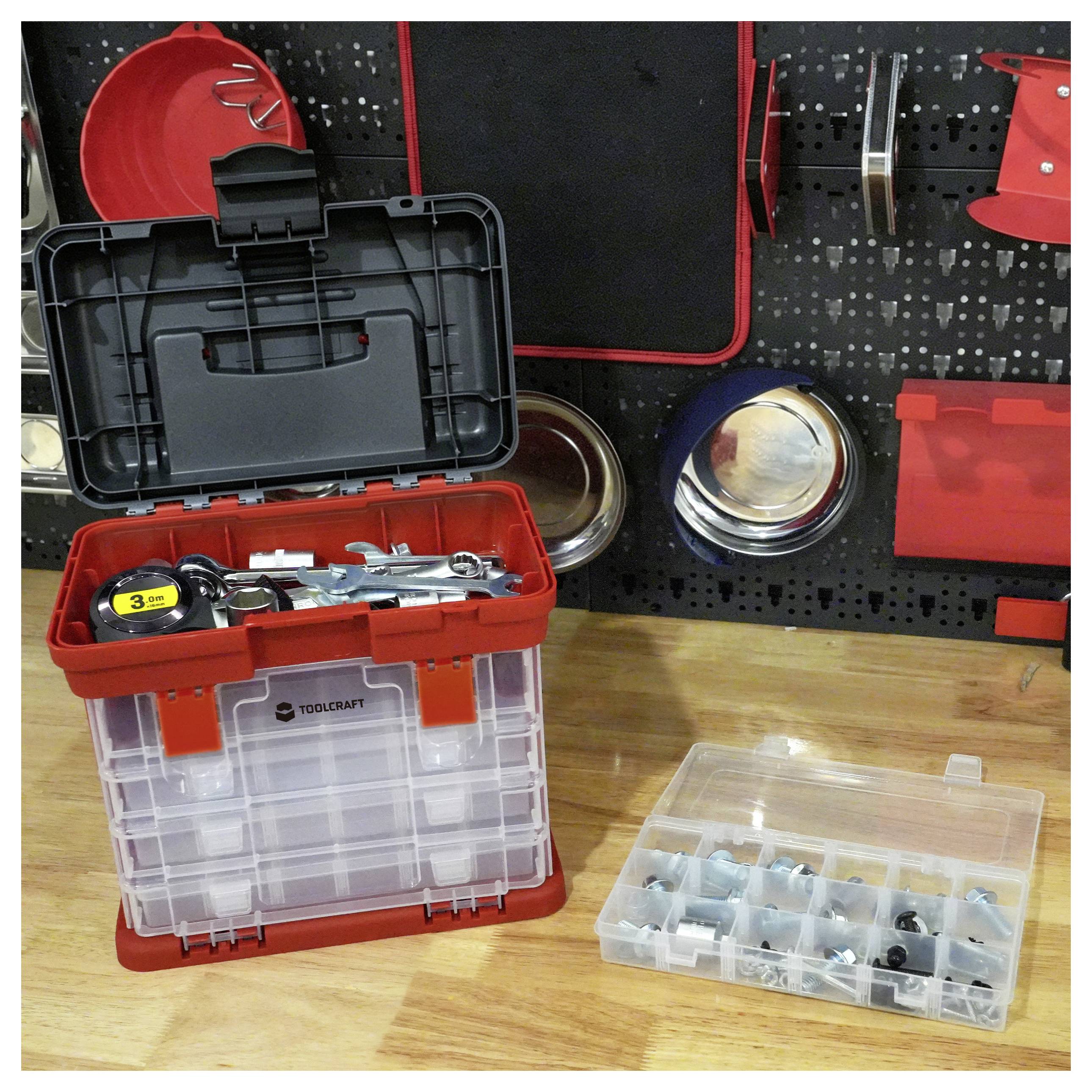 Offene rote Toolcraft-Lagerkiste mit Handwerkzeugen auf einer Werkbank, neben einer durchsichtigen Organizer-Box mit kleinen Befestigungselementen und einer Werkzeugwandausstellung im Hintergrund.