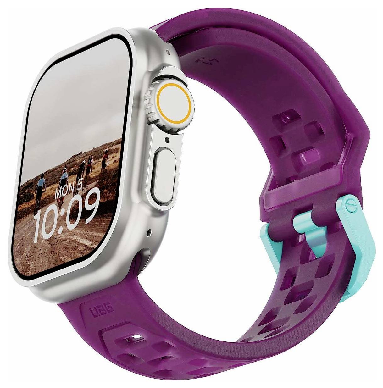 Silberne Smartwatch mit violettem sportlichem Armband und türkisfarbenem Verschluss, in schräger Ansicht mit einer Wüstenszene auf dem Display, auf dem 