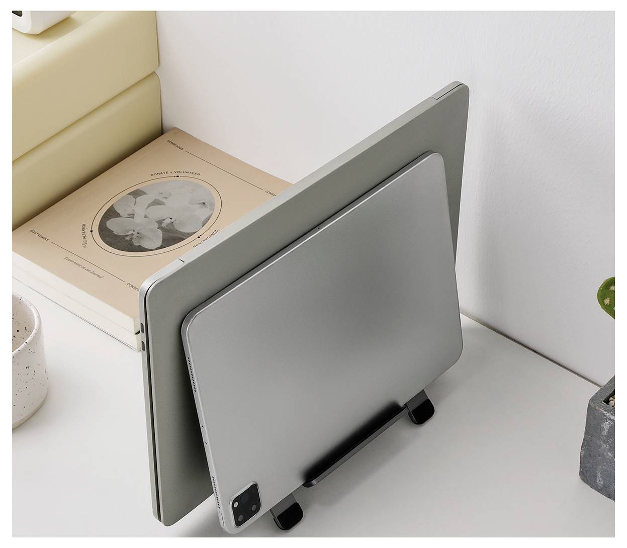 Zwei Tablets oder laptopähnliche Geräte stehen aufrecht auf einem Schreibtisch in einem minimalistischen Arbeitsbereich, eines vor dem anderen.