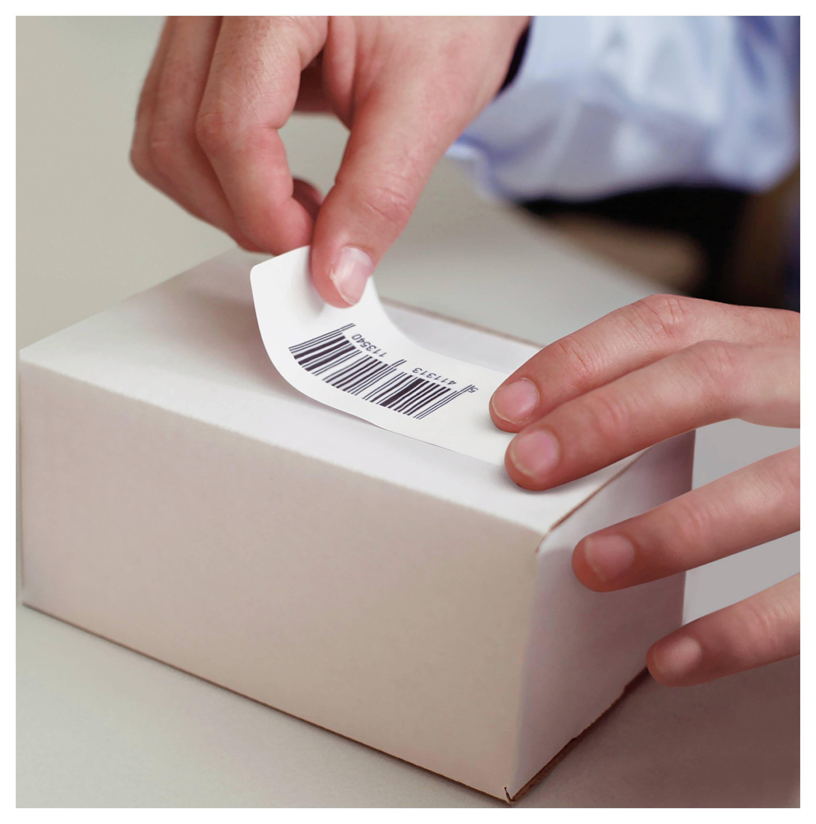 Hände schälen ein Barcode-Etikett von einer weißen Geschenkbox ab und deuten auf das Öffnen oder Überprüfen des Pakets hin.