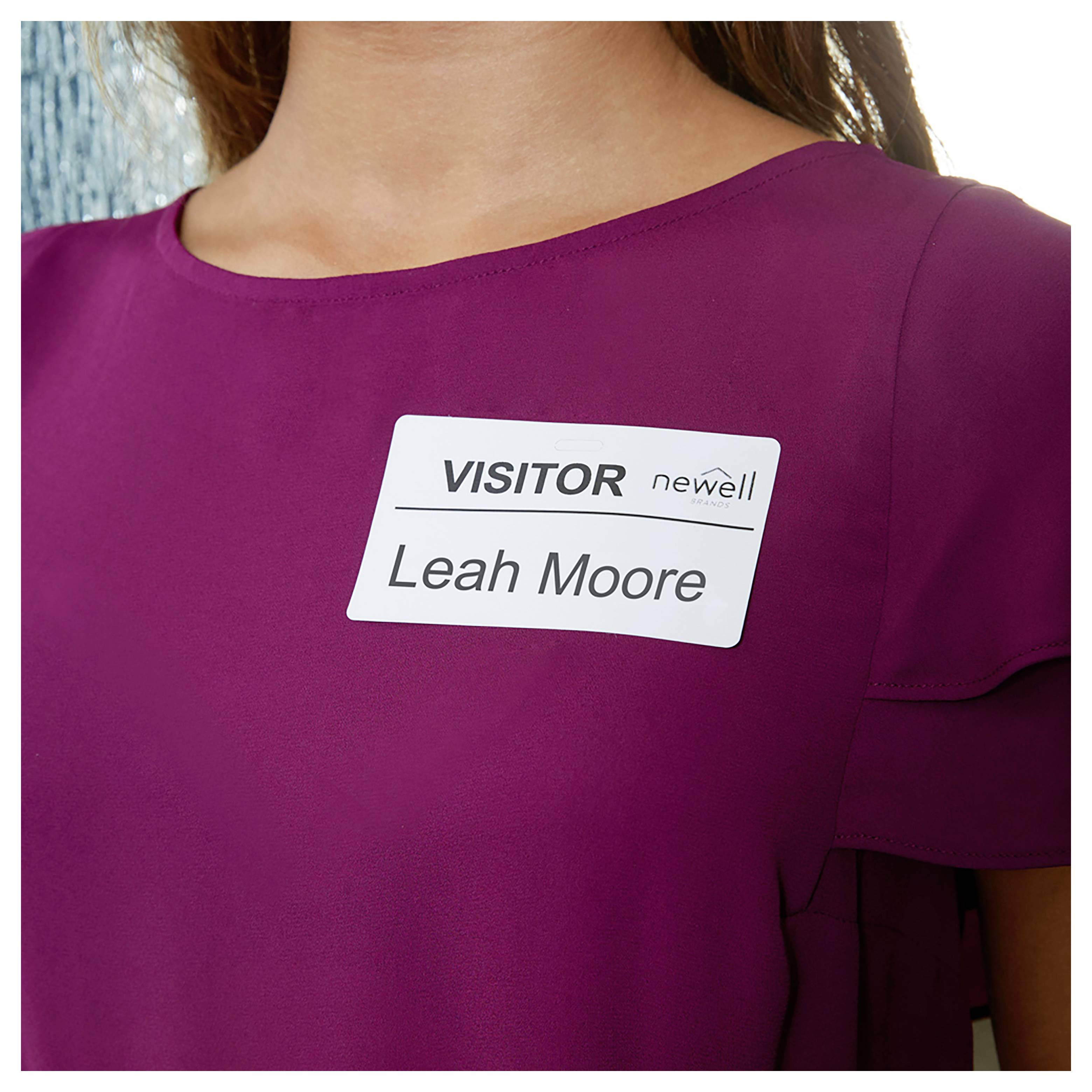 Besucherausweis auf einem Magenta-Hemd einer Frau mit der Aufschrift „Leah Moore