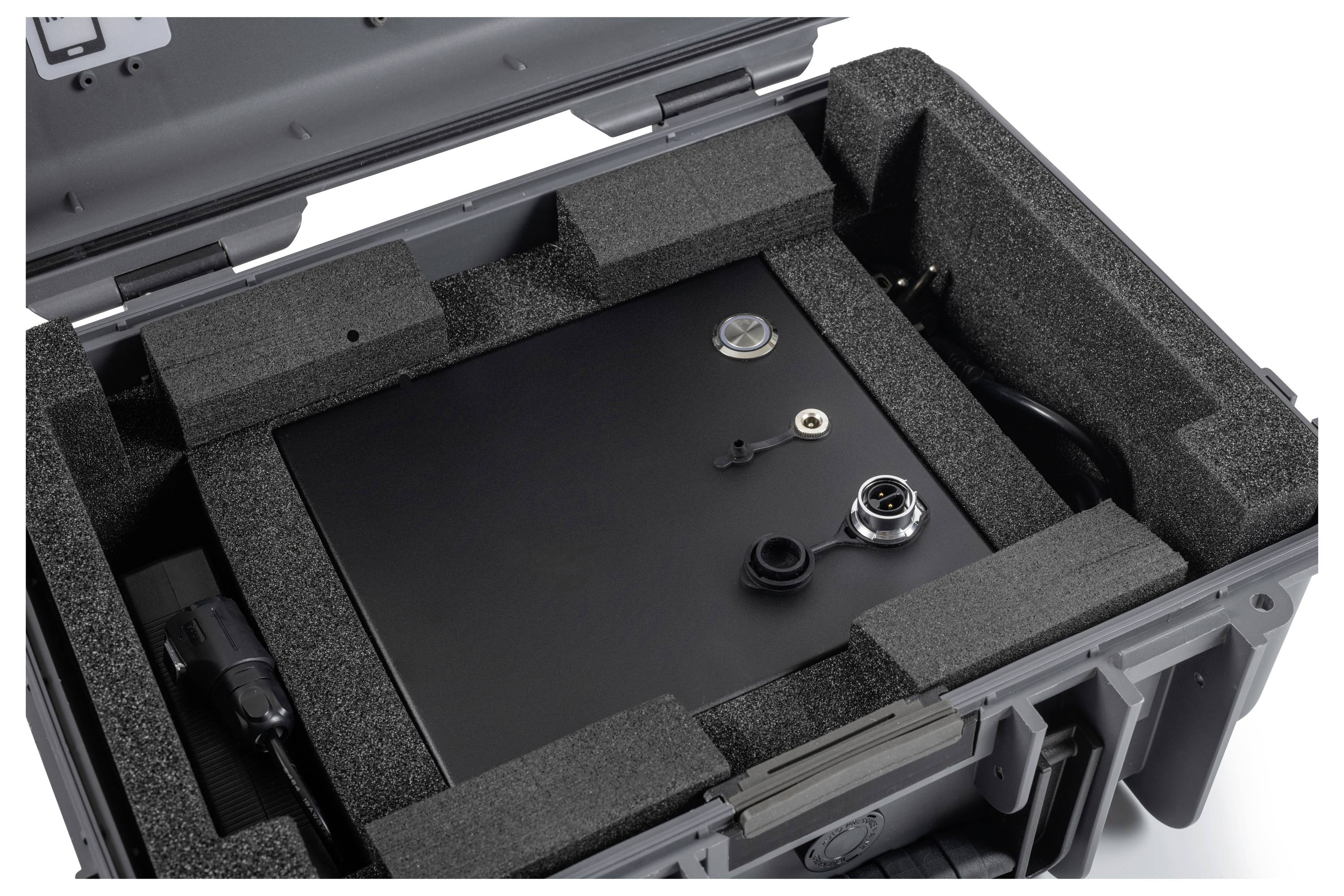 Offener Hartschalenkoffer mit Schaumstoffpolsterung, der eine schwarze Metallausrüstungsbox und Steckerverbindungen im Inneren hält.