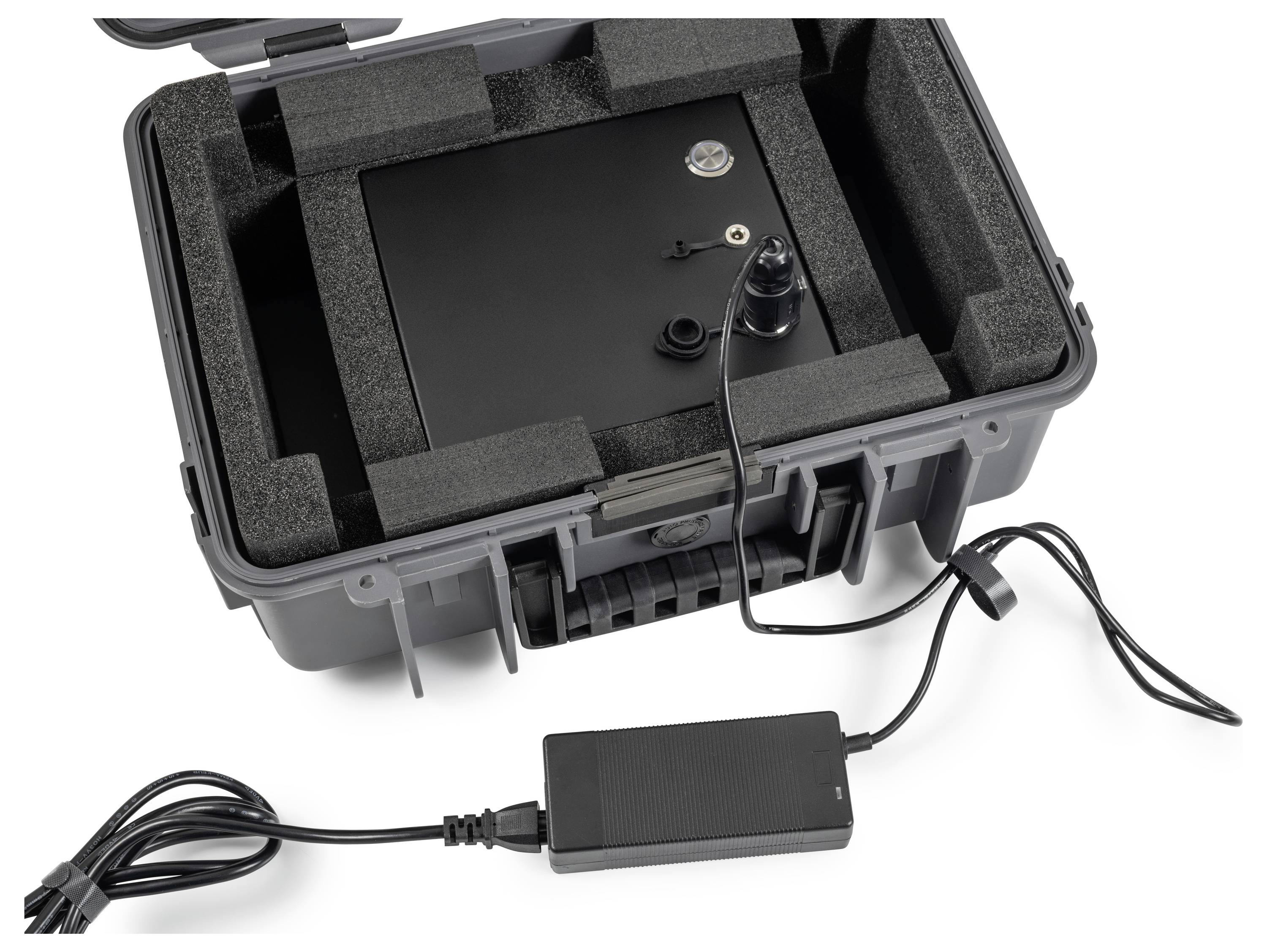 Offener schwarzer Schutzkoffer mit Schaumstoffeinlage, die ein schwarzes elektronisches Gerät und einen angeschlossenen Stromadapter mit Kabel hält.