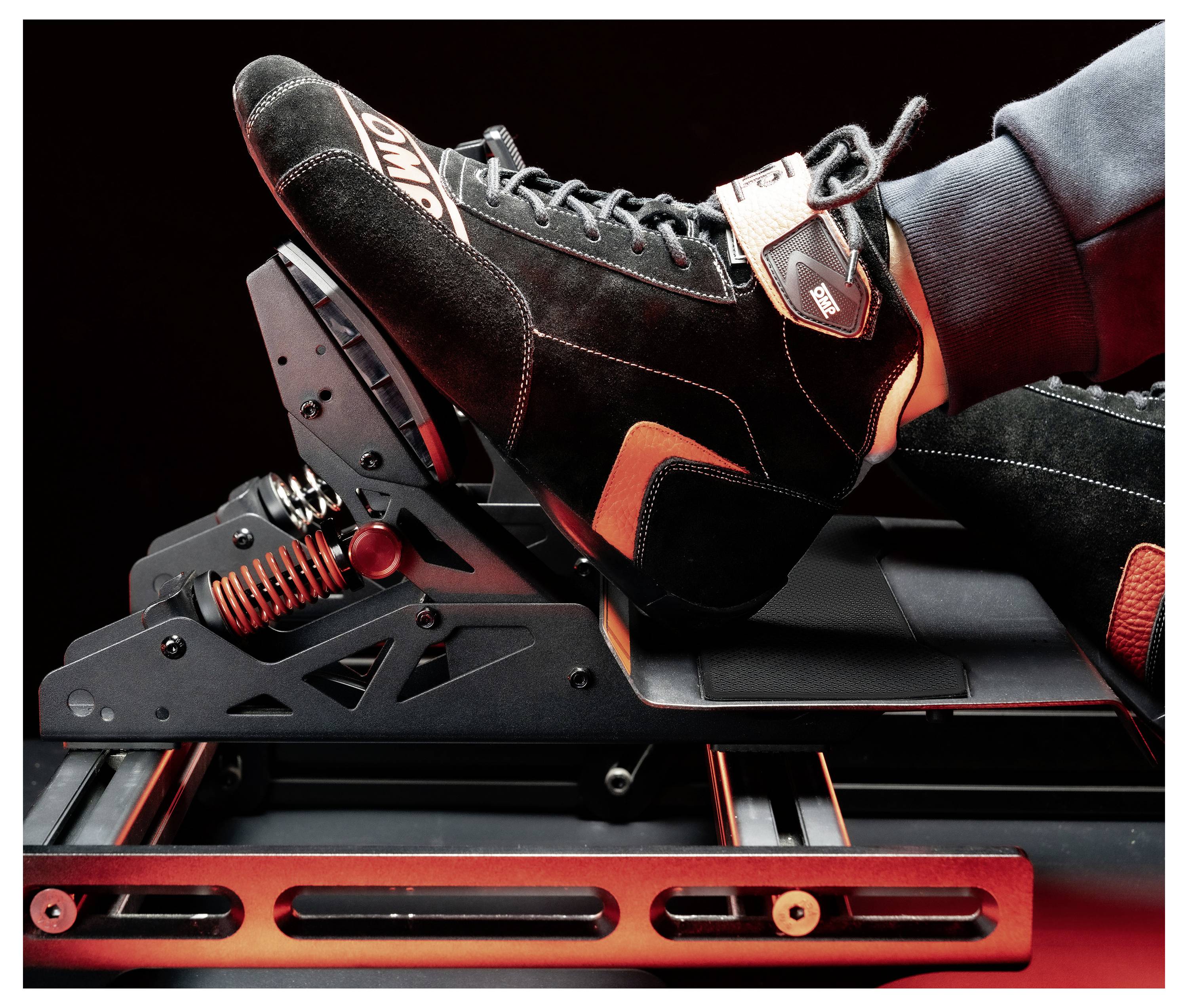 Nahaufnahme einer Person, die einen Rennschuh trägt und ein schwarzrotgepunktetes Pedal-Simulator- oder Fußstützgerät benutzt, wobei der Fuß an Ort und Stelle festgeschnallt ist.