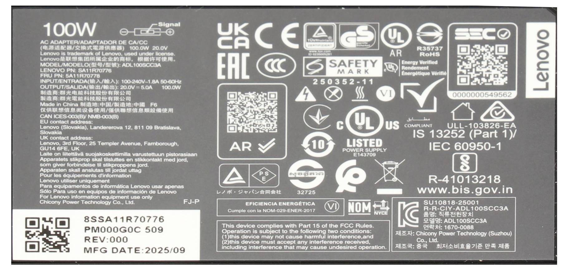 Nahaufnahme eines Lenovo 100-W-Netzteils mit mehreren Zertifizierungslogos, QR-Codes, Modell- und behördlichen Angaben sowie Herstellungsdatum.