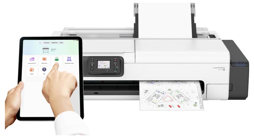 Eine Person benutzt ein Tablet, um einen großformatigen Drucker zu steuern, während dieser ein farbiges technisches Diagramm druckt.