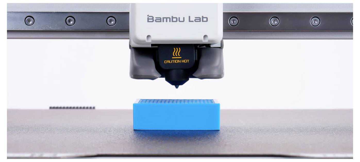 Bambu Lab 3D-Drucker-Düse druckt einen blauen rechteckigen Block auf der Bauplattform.