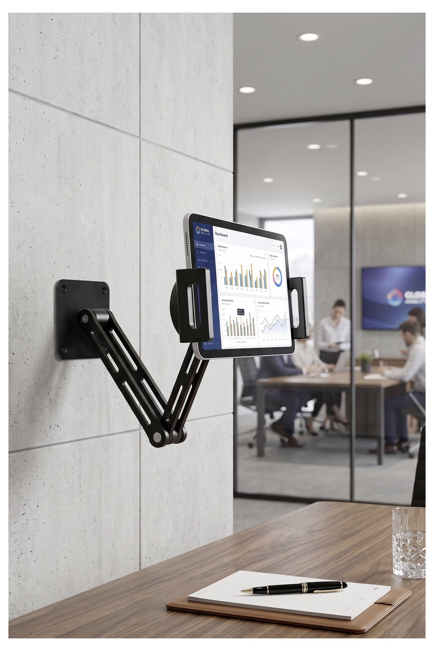 Ein an der Wand montierter verstellbarer Monitorarm, der einen Bildschirm mit Diagrammen in einem modernen Büro-Besprechungsraum hält, über einem Schreibtisch mit Notizbuch und Stift.