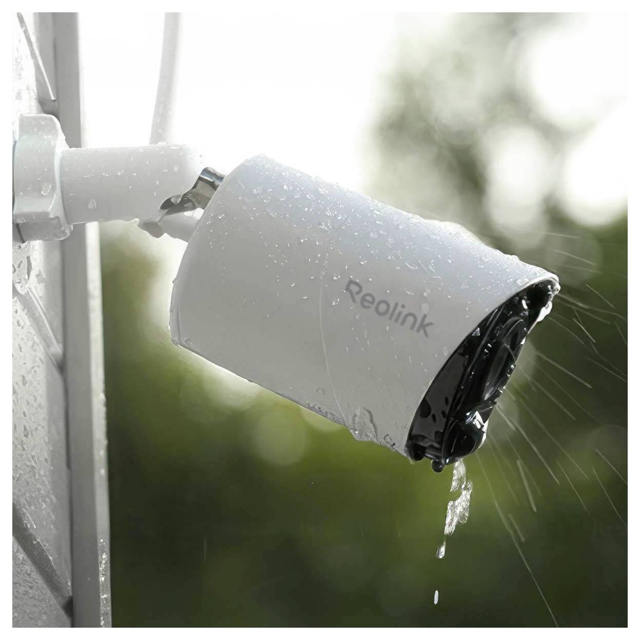 Weiße Reolink Outdoor-Sicherheitskamera an einer Wand montiert, nass vom Regen und nach außen ausgerichtet, mit Wasser, das vom Linsengehäuse tropft.