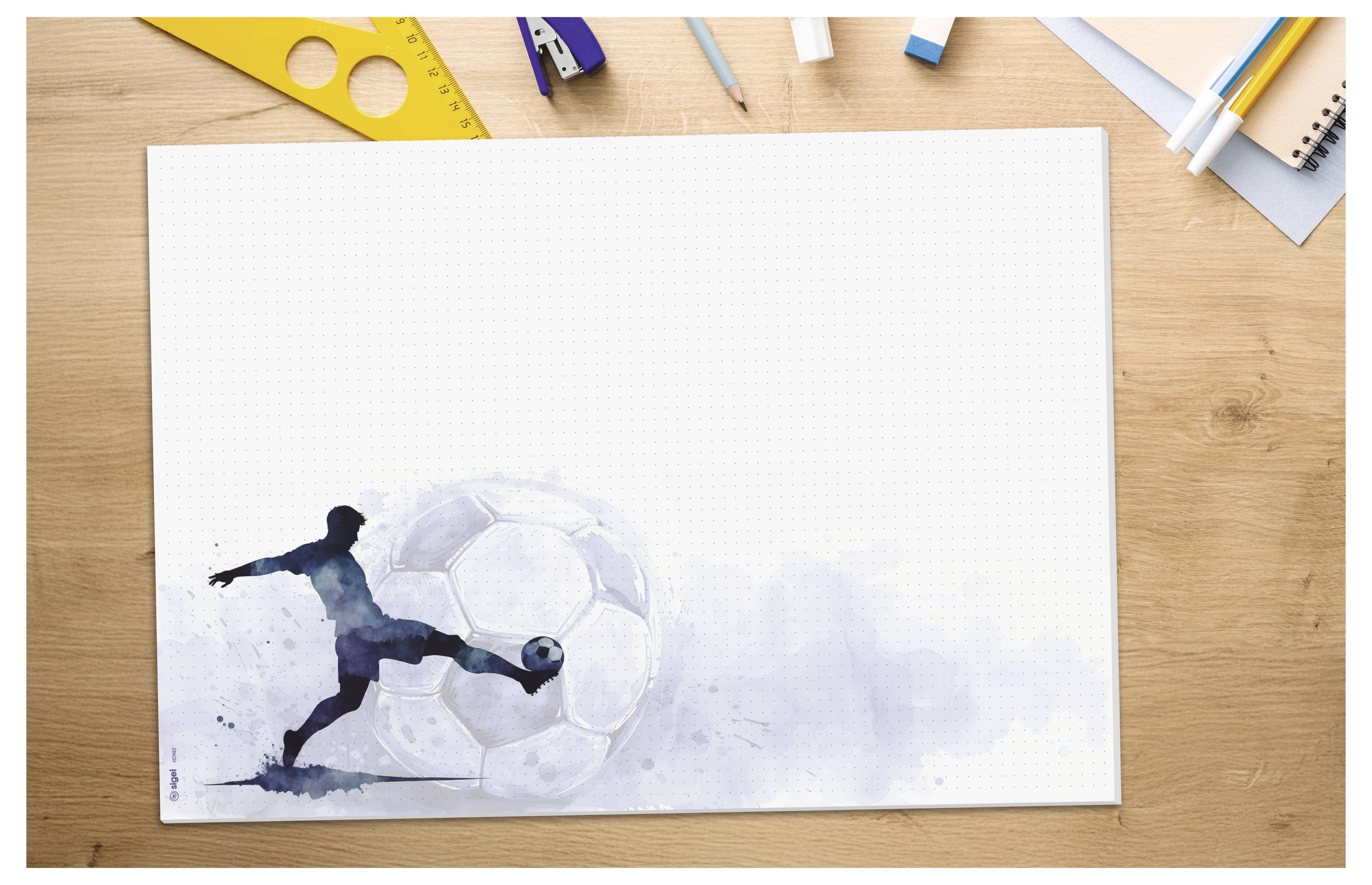 Aquarellillustration eines Fußballspielers, der einen Ball tritt, gedruckt auf einem leeren Blatt auf einem Holzschreibtisch mit Bleistiften und Zeichenwerkzeugen drumherum.