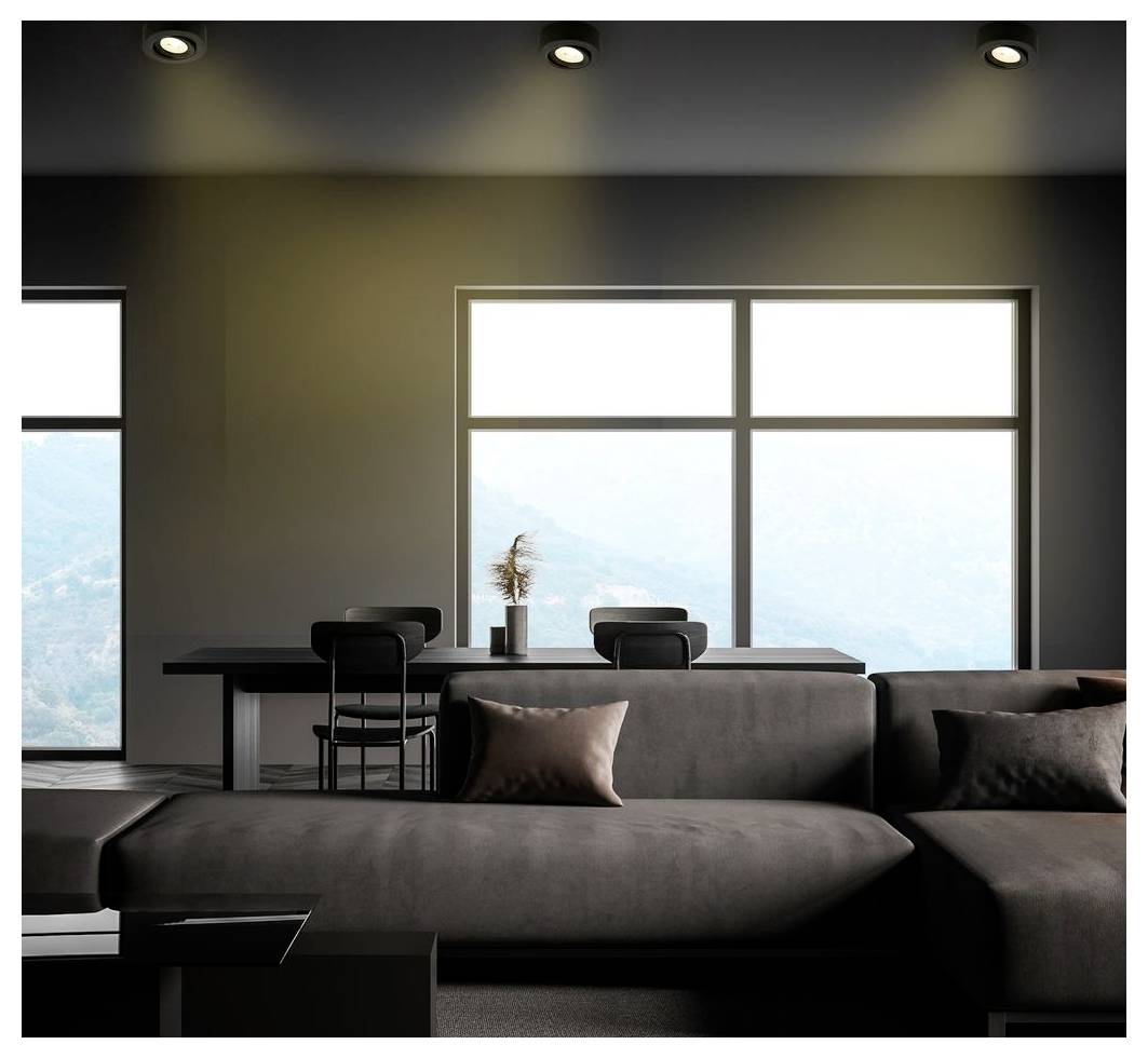 Modernes minimalistisches Wohnzimmer mit dunklem Ecksofa, Esstisch und großen Fenstern mit Blick auf eine helle Berglandschaft.