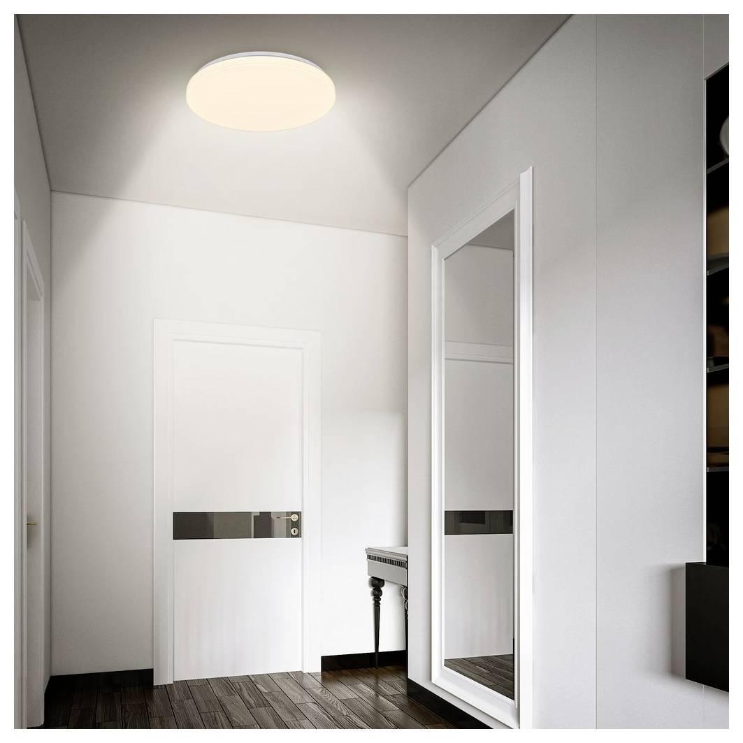 Minimalistischer weißer Flur oder Ankleidebereich mit einer Tür, einem Ganzkörperspiegel und einem kleinen Tisch unter einer Deckenleuchte.