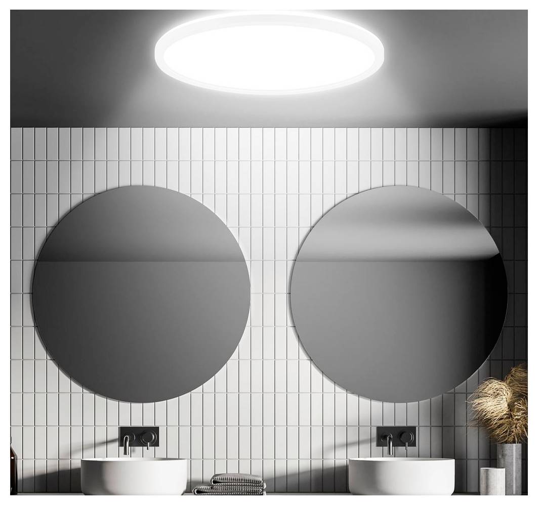 Modernes Badezimmer mit zwei runden Spiegeln über doppelten Aufsatzwaschbecken, beleuchtet durch eine Deckenleuchte und vor weißen Fliesenmauerwerk gestellt.