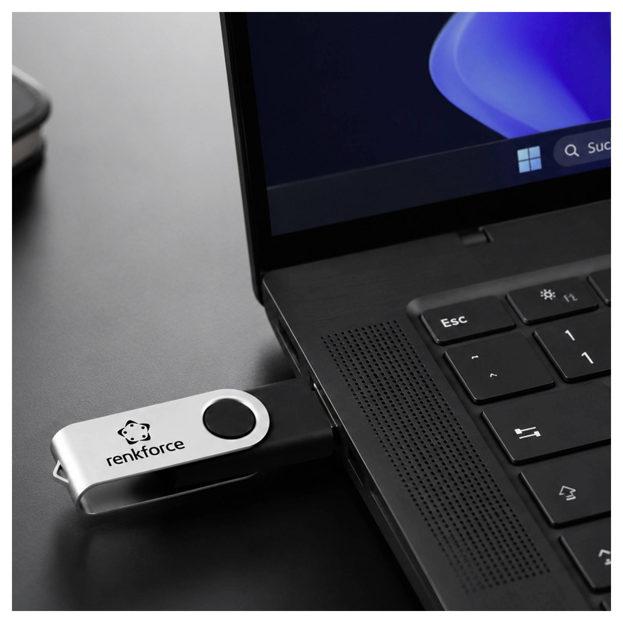 Ein Laptop mit einem USB-Speicherstick, der in seinen seitlichen Anschluss gesteckt ist und das Logo 