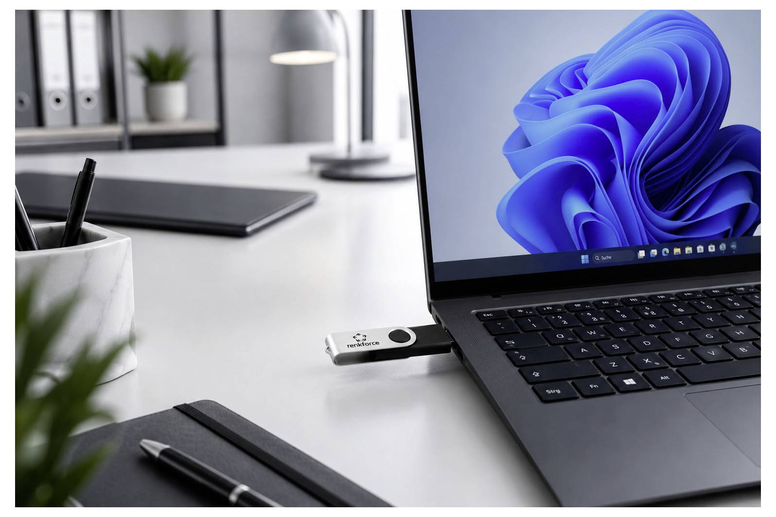 Laptop auf einem Schreibtisch mit eingefügtem USB-Sicherheitsschlüssel, was auf sichere Anmeldung oder Datenschutz in einem Office-Arbeitsbereich hindeutet.
