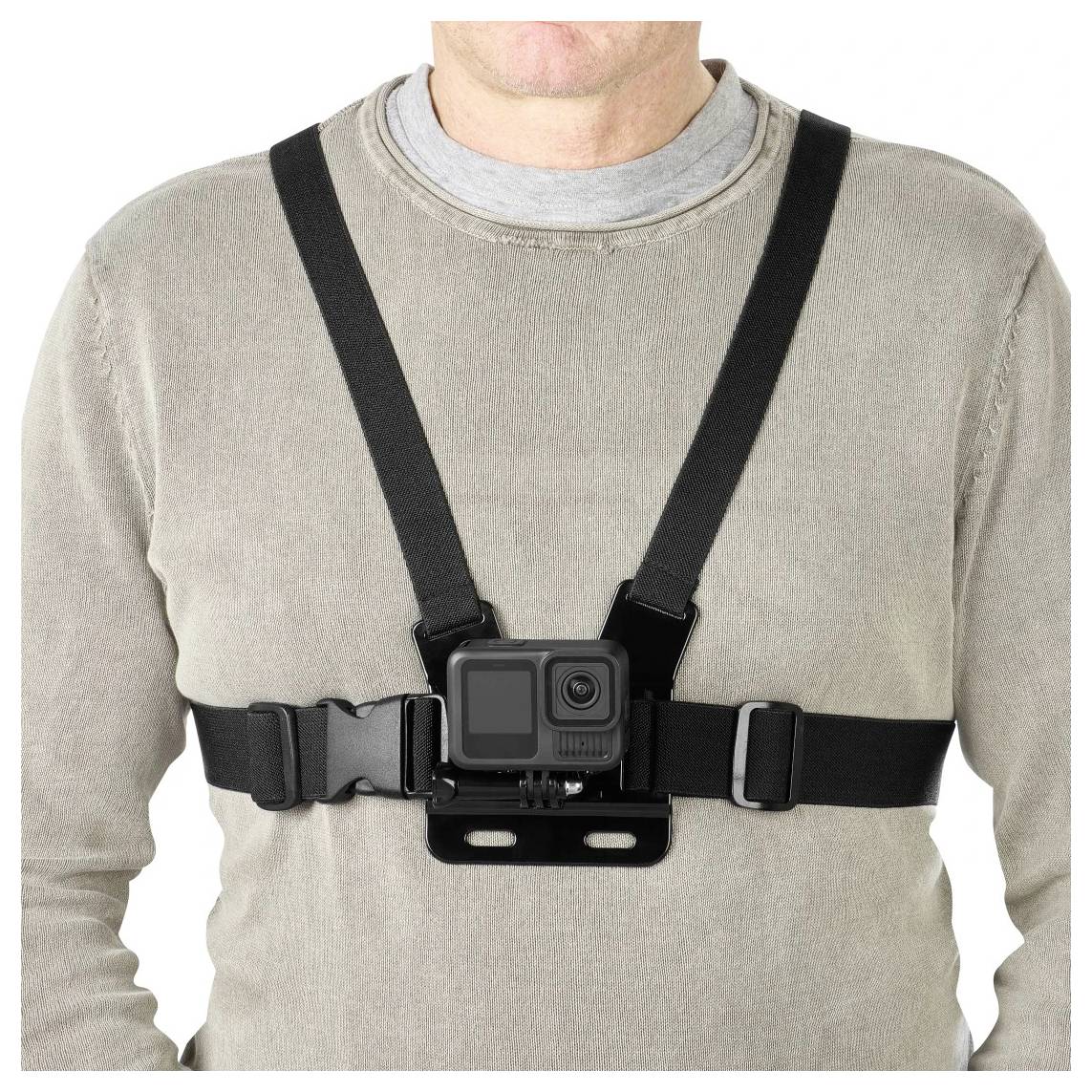 Person wearing a chest-mounted action camera harness over a gray shirt on a plain white background.Schöne Frau, die über einem grauen Hemd ein auf der Brust montiertes Actionkamera-Tragesystem vor weißem Hintergrund trägt.