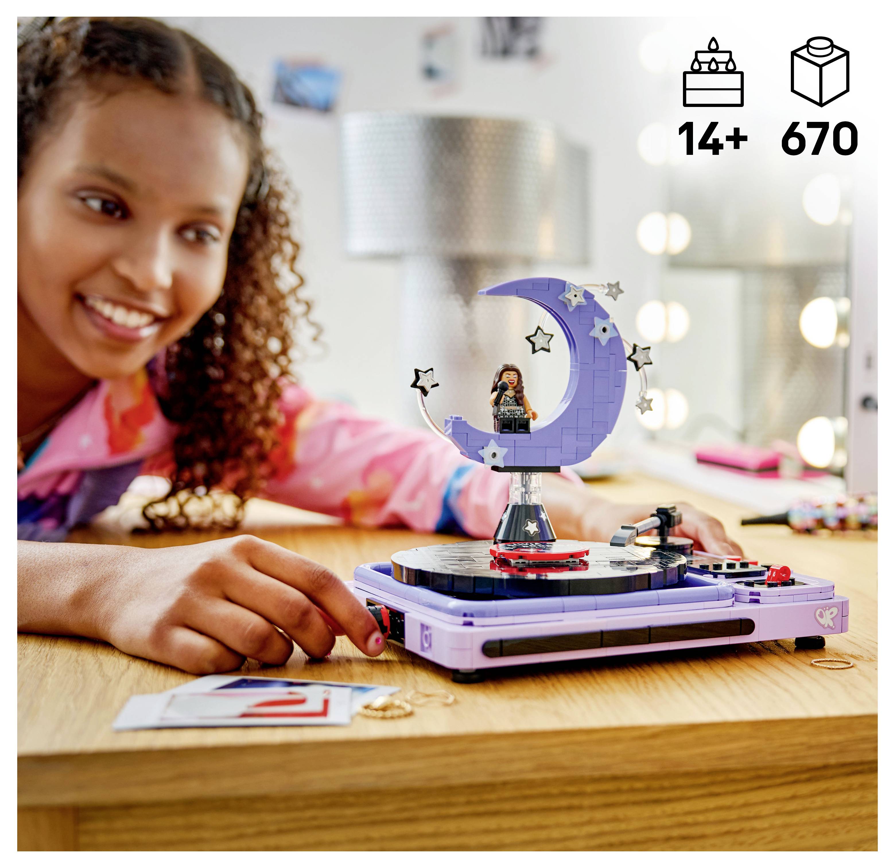 Lächelndes Mädchen baut ein LEGO-ähnliches Monddisplay auf einem Drehteller-Set auf, mit „14+