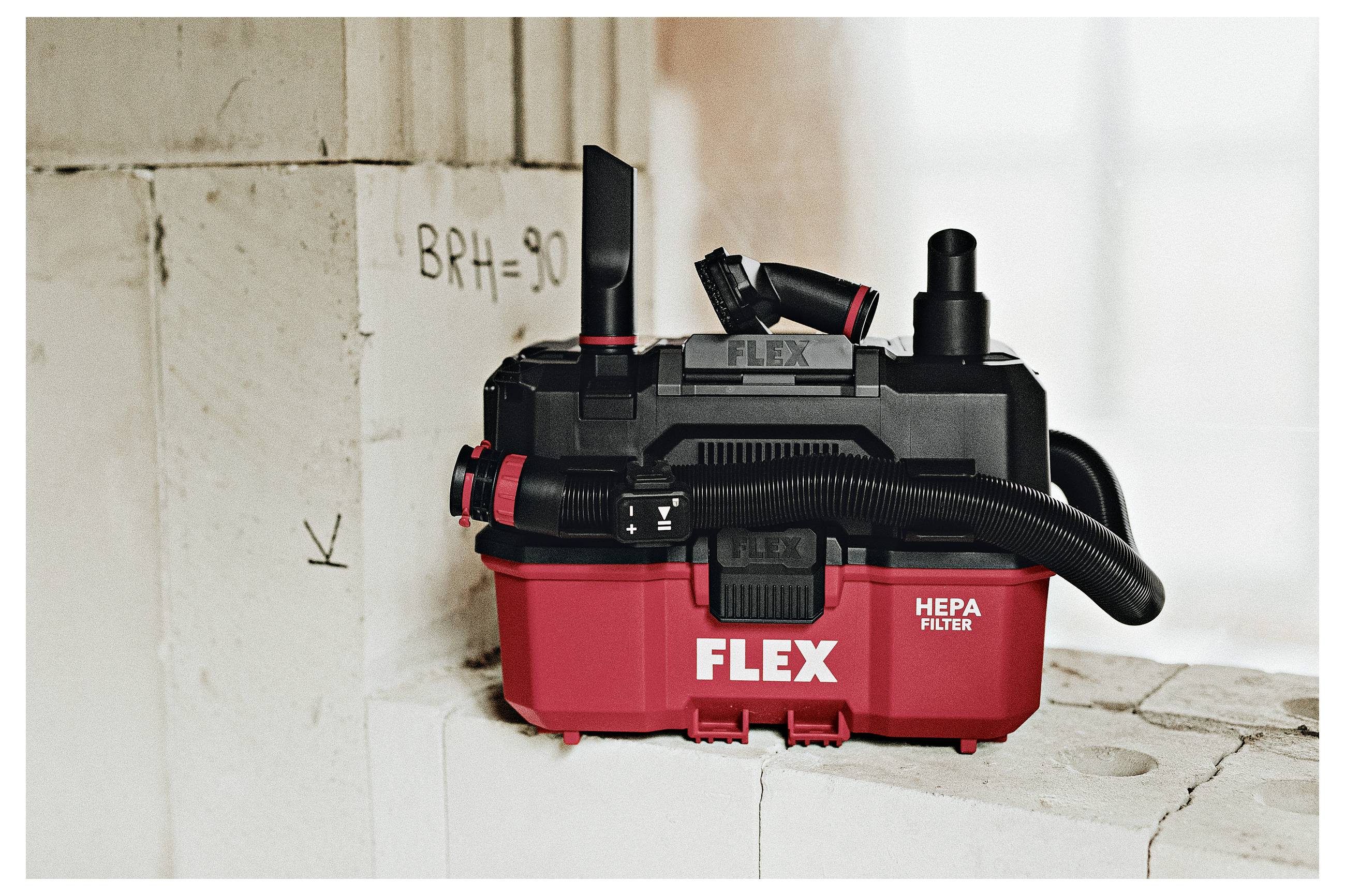 Roter FLEX Staubsauger mit HEPA-Filter, der auf einem staubigen Baugerüst neben einer mit „BRH=90