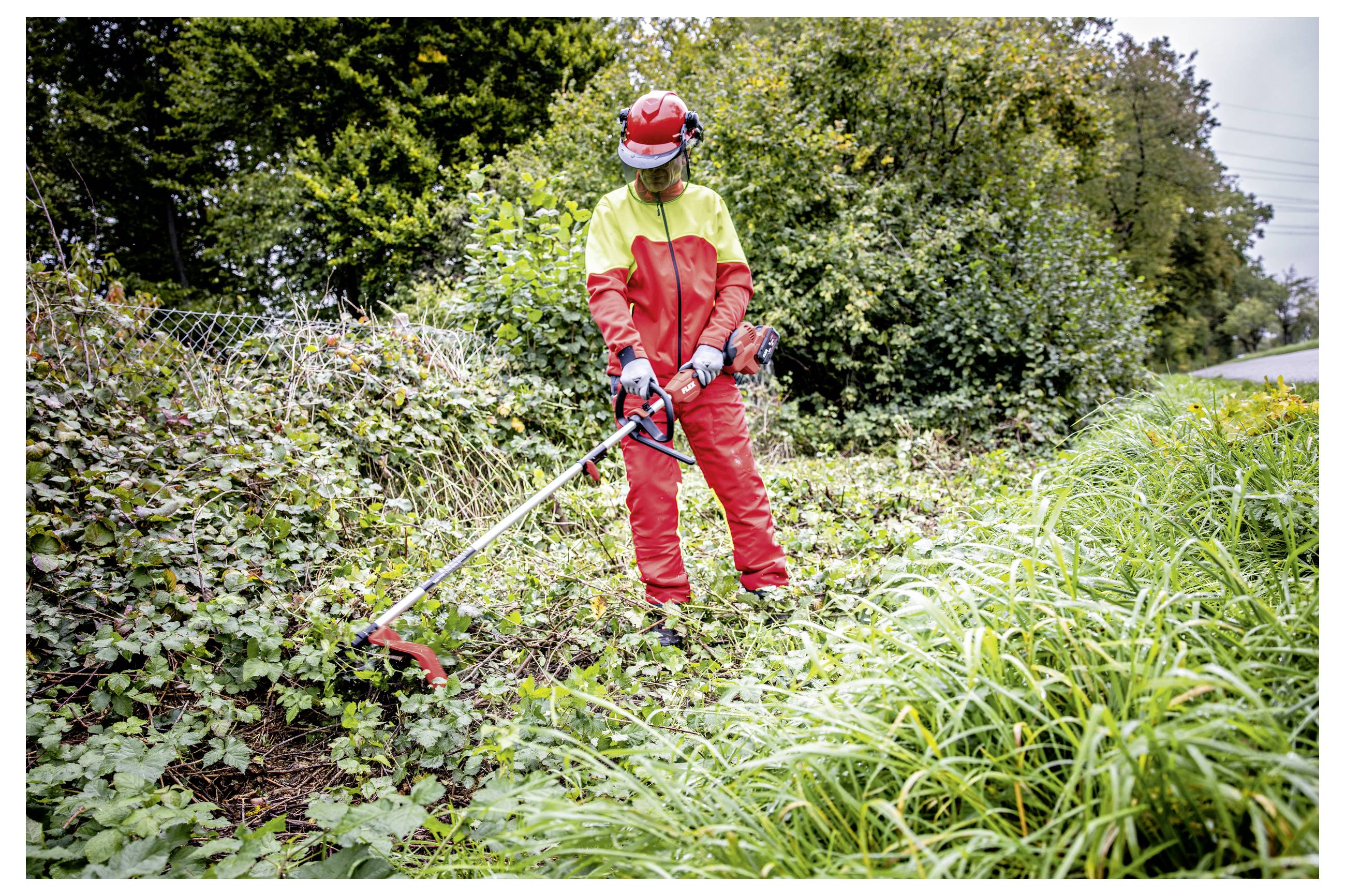 Arbeiter in roter und gelber Schutzausrüstung nutzt einen Freischneider, um überwucherte Vegetation entlang einer Straße oder eines Weges freizuschneiden.