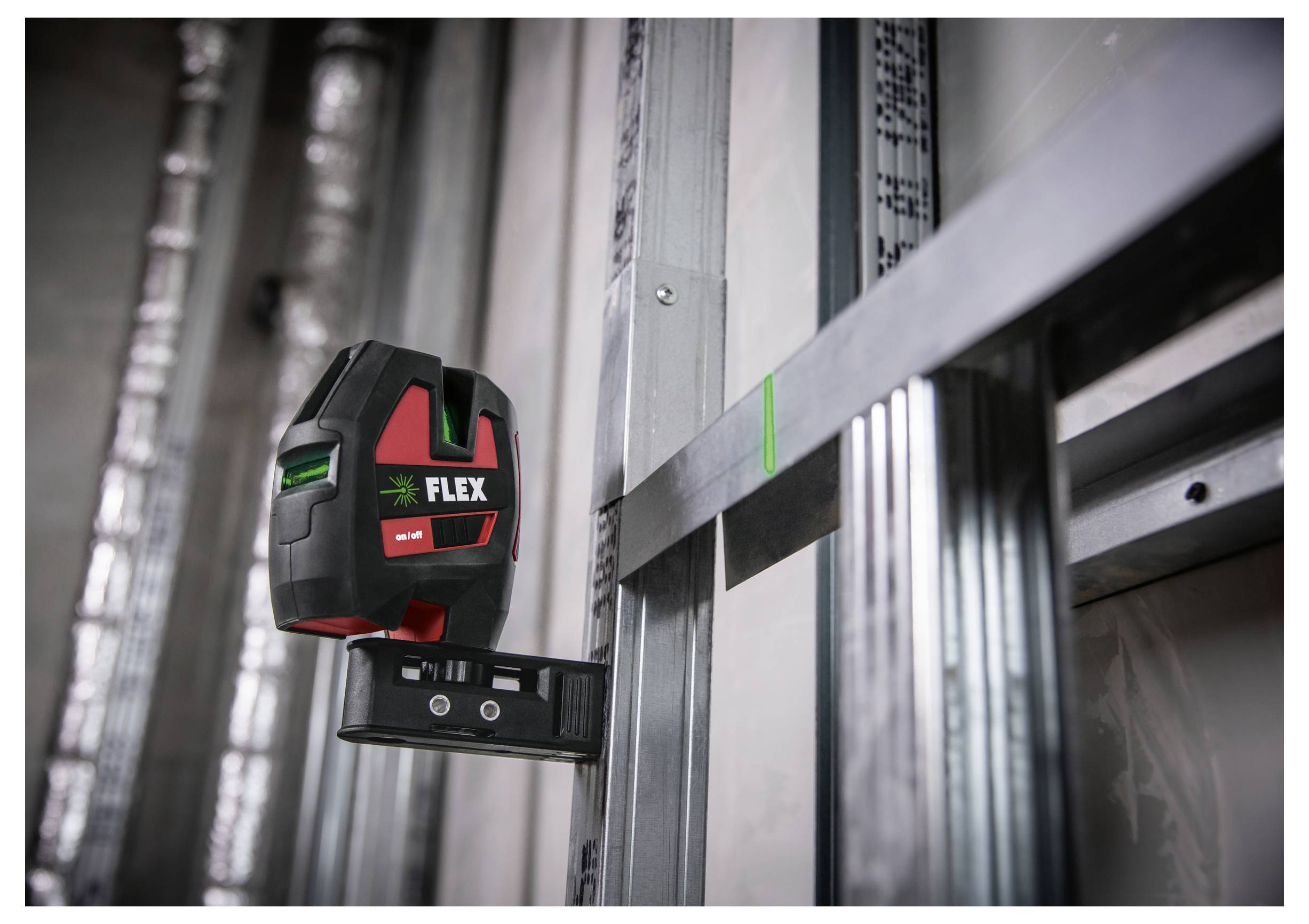 Ein FLEX-Laserpegel, der auf einer Metallhalterung montiert ist, projiziert eine grüne Ausrichtungslinie auf eine Wand oder Ständerwerk.